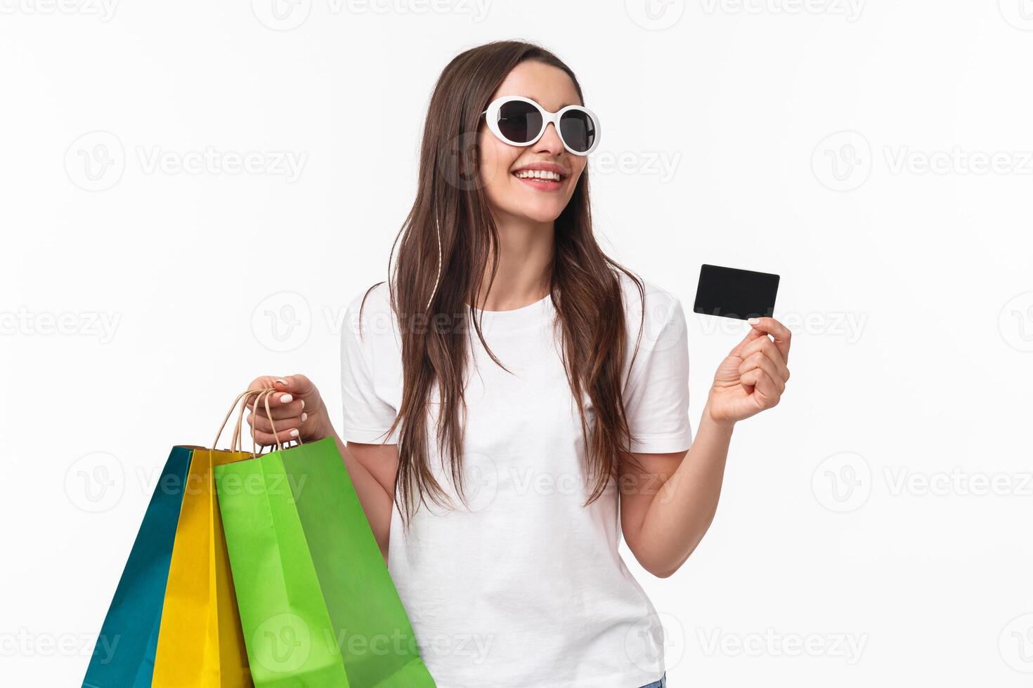 Shopping, leisure and lifestyle concept. Portrait of carefree attractive, feminine young woman shop in stores, giving her credit card to clerk as walking away from mall with shop bags photo