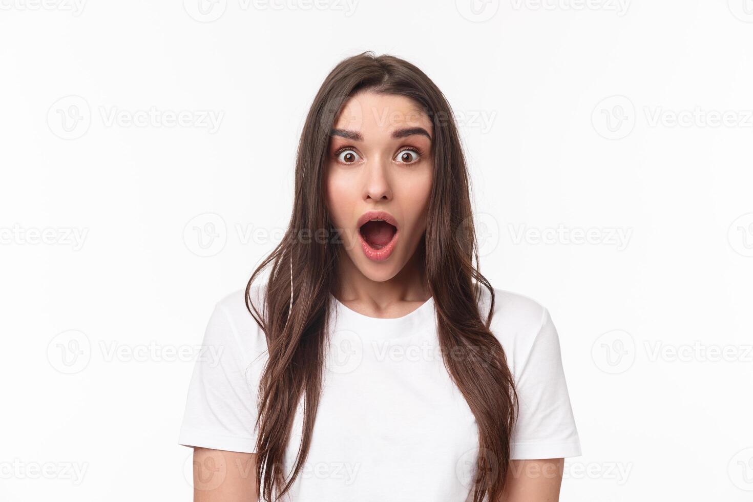 Close-up portrait of surprised and startled young brunette female drop jaw from spilled tea, gossiping and hear something incredible, open mouth fascinated looking camera impressed photo