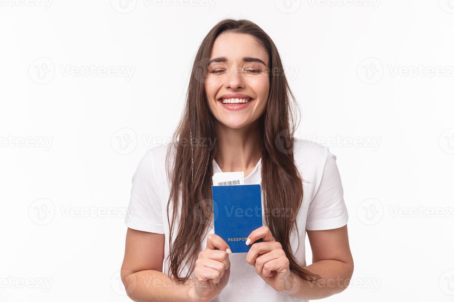 Travelling, holidays, summer concept. Close-up portrait of happy, dreamy girl feeling happy finally travel, holding passport with plane ticket, waiting in airport, standing white background photo