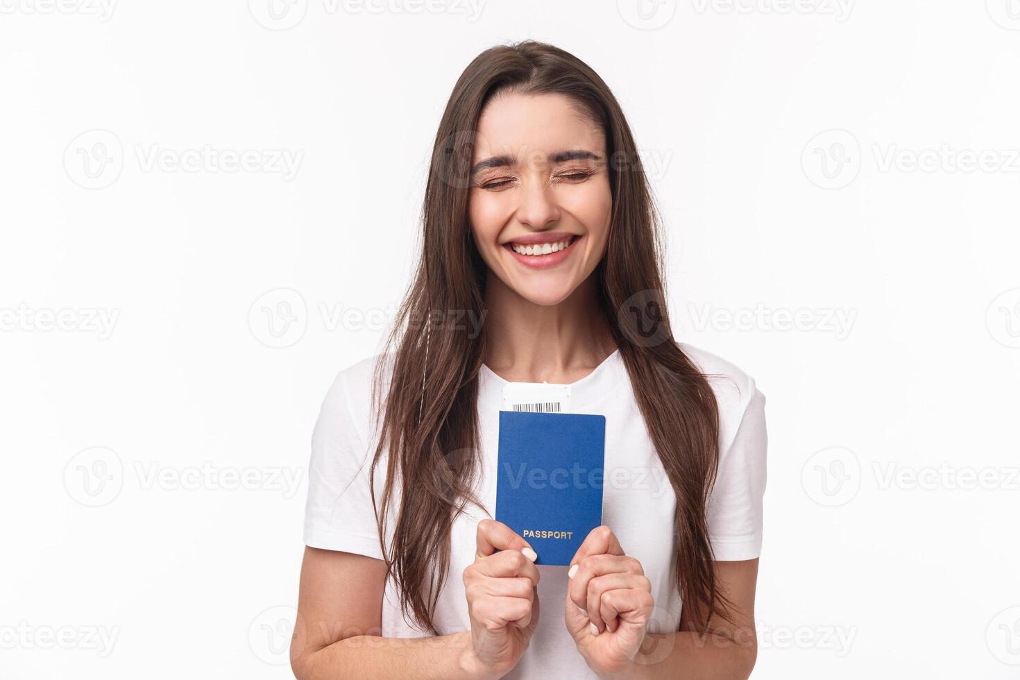 Travelling, holidays, summer concept. Portrait of cheerful happy, laughing girl close eyes and smiling enthusiastic, receive her pasport to travel abroad, finally sitting in airport ready for journey photo