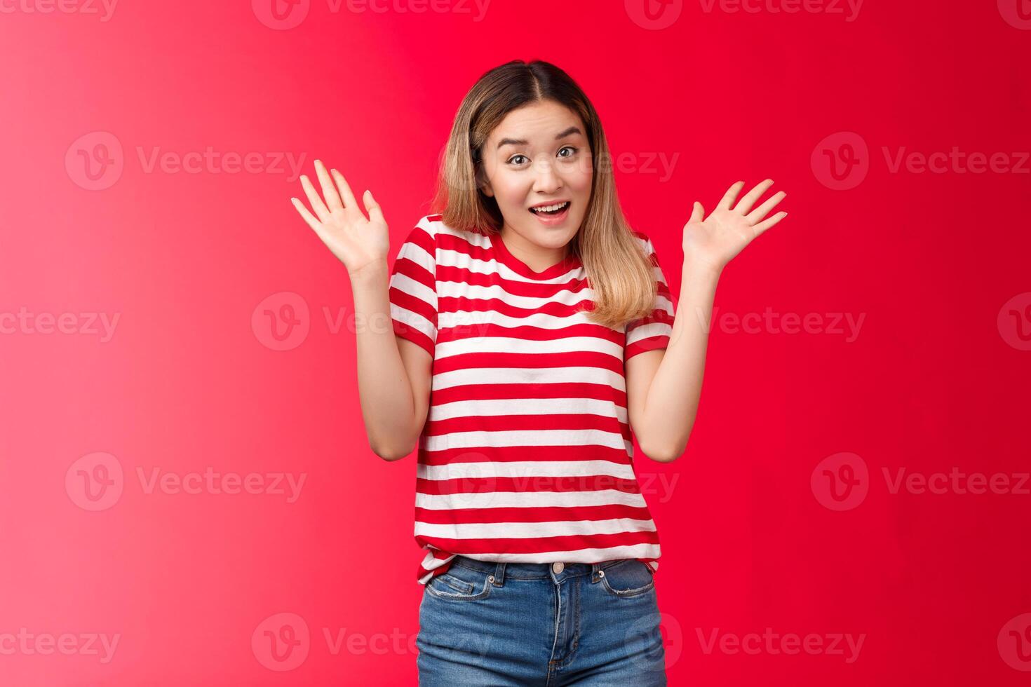 Not me, I am innocent. Silly pretty asian modern girl lift hands up shrugging smiling questioned, puzzled to answer, have no idea, standing uninvolved red background surrender photo