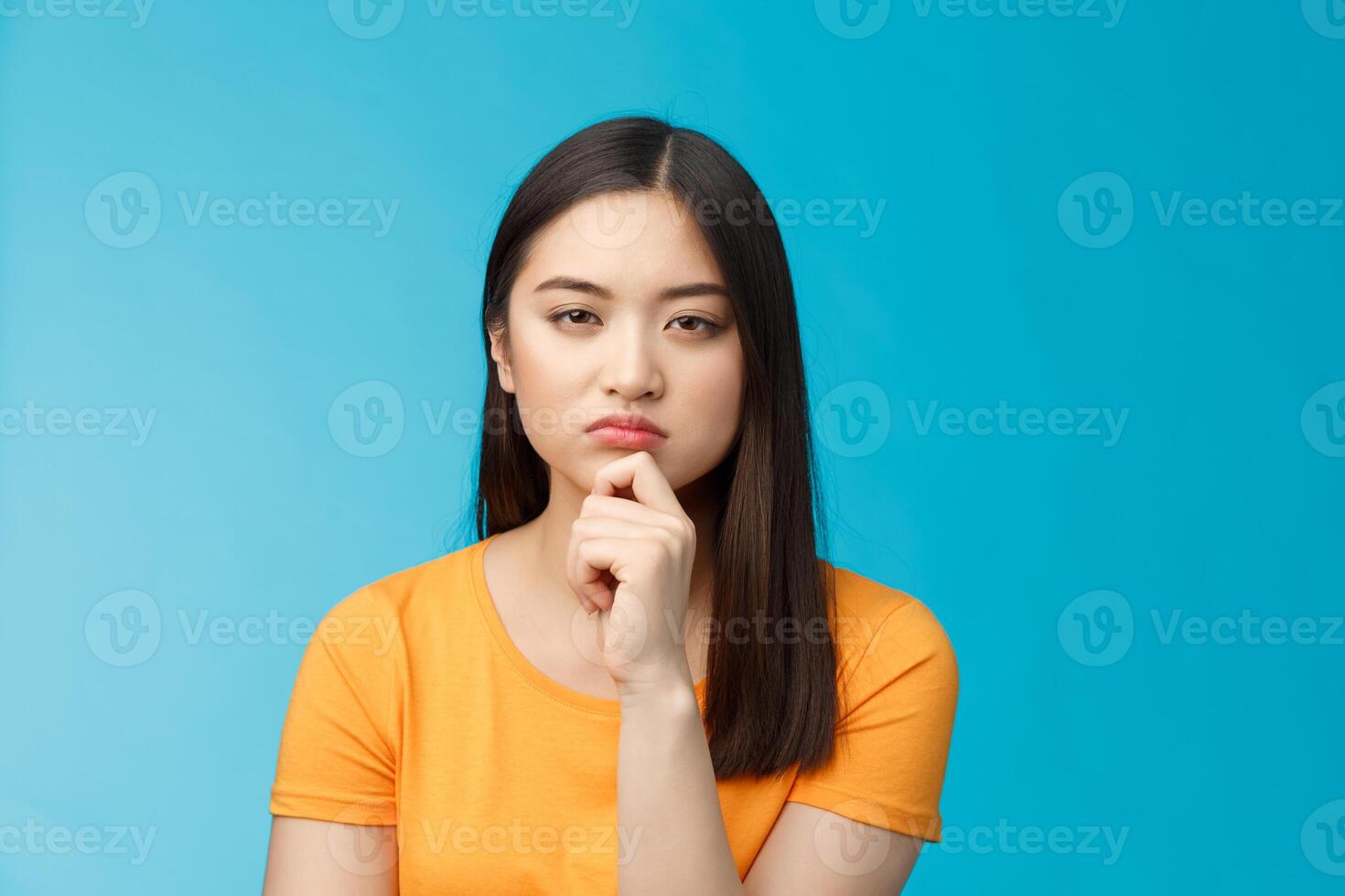 Close-up serious-looking suspicious female asian look disbelief, pondering, solving riddle, squinting hesitant disbelief, frowning suspect something wrong, thinking, focus stare, blue background photo