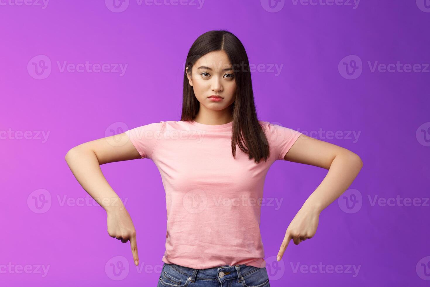 Serious-looking upset insecure asian female fighting stop cruel animal behaviour, pointing fingers down disappointed, look camera sincere fed up, standing depressed unsatisfied, purple background photo