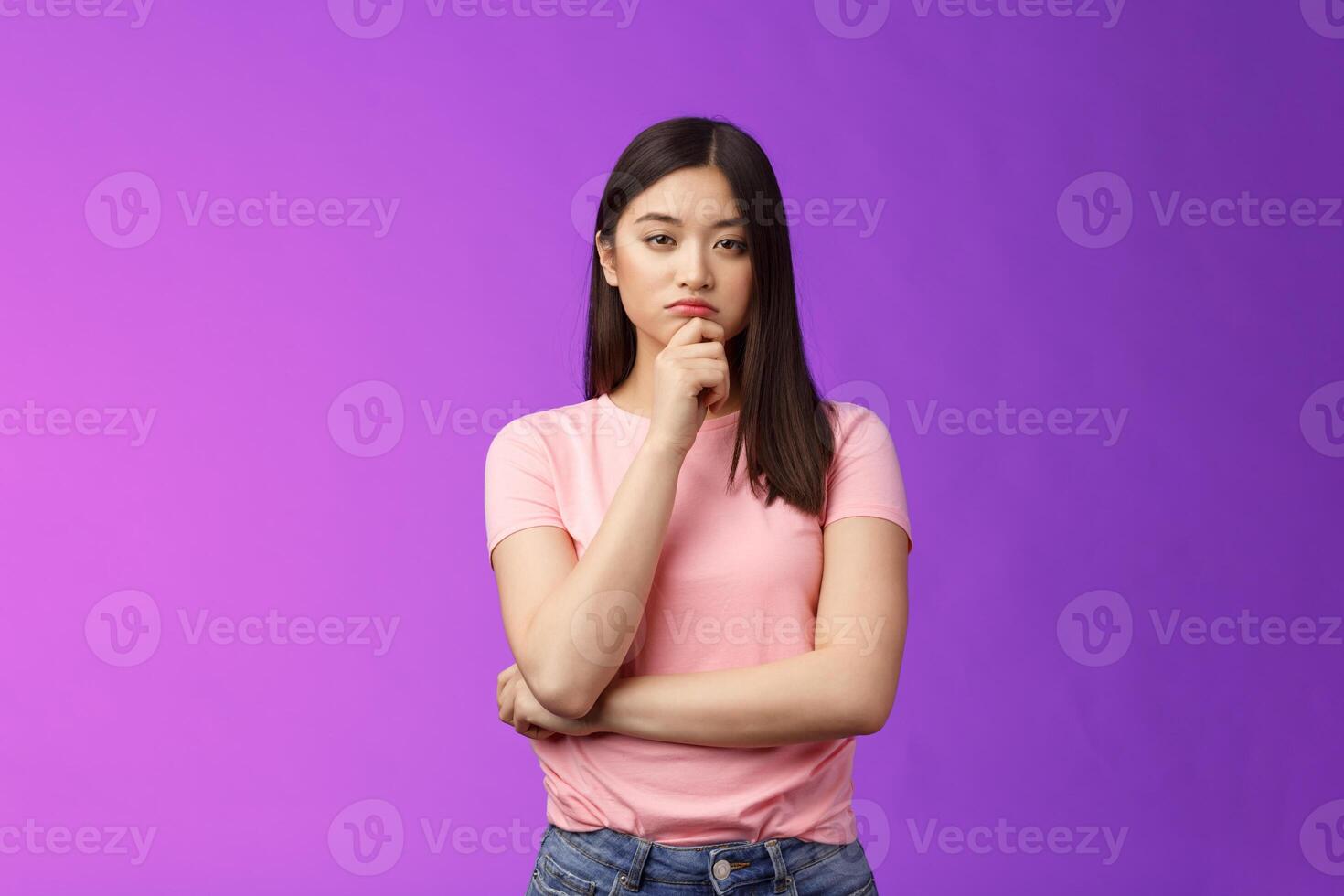 Judgemental serious-looking smart asian girl give expert look, touch chin thoughtful, squinting suspicious uncertain, make decision, choosing product, thinking, pondering plan, purple background photo