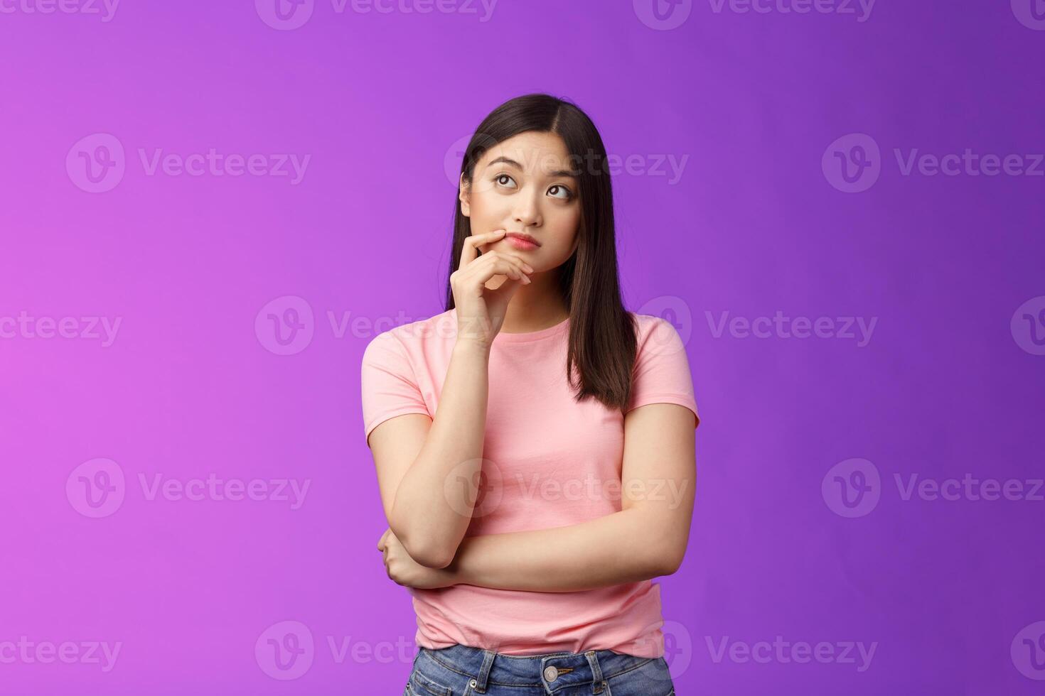 Thoughtful creative stylish asian girlfriend thinking-up perfect b-day gift, touch chin thoughtful look upper left corner, pondering, imaging in mind ideas, stand purple background photo