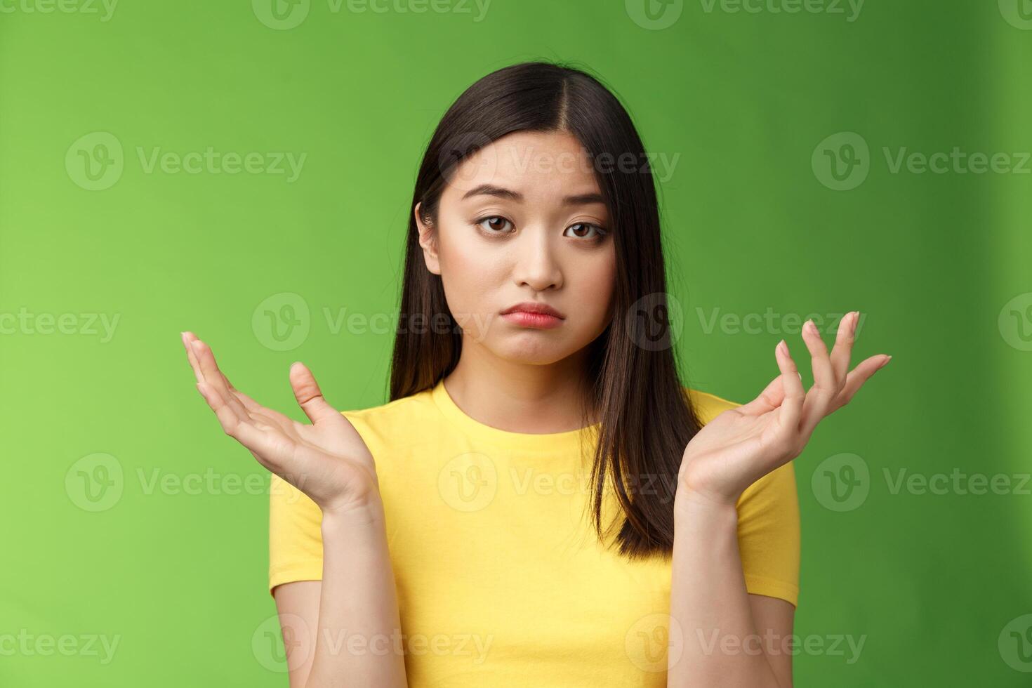 Close-up confused unemotive brunette woman spread hands sideways full dibelief, questioned what happening, look apathy reluctant, stand green background frustrated, no emotions photo