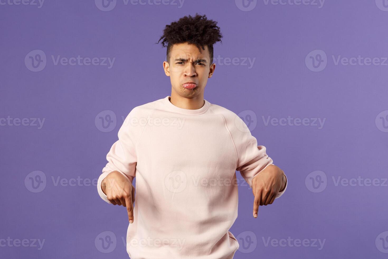 Portrait of upset and disappointed man talking about his bad experience with awful app, sulking and frowning offended, feel uneady and distressed, pointing fingers down dissatisfied photo