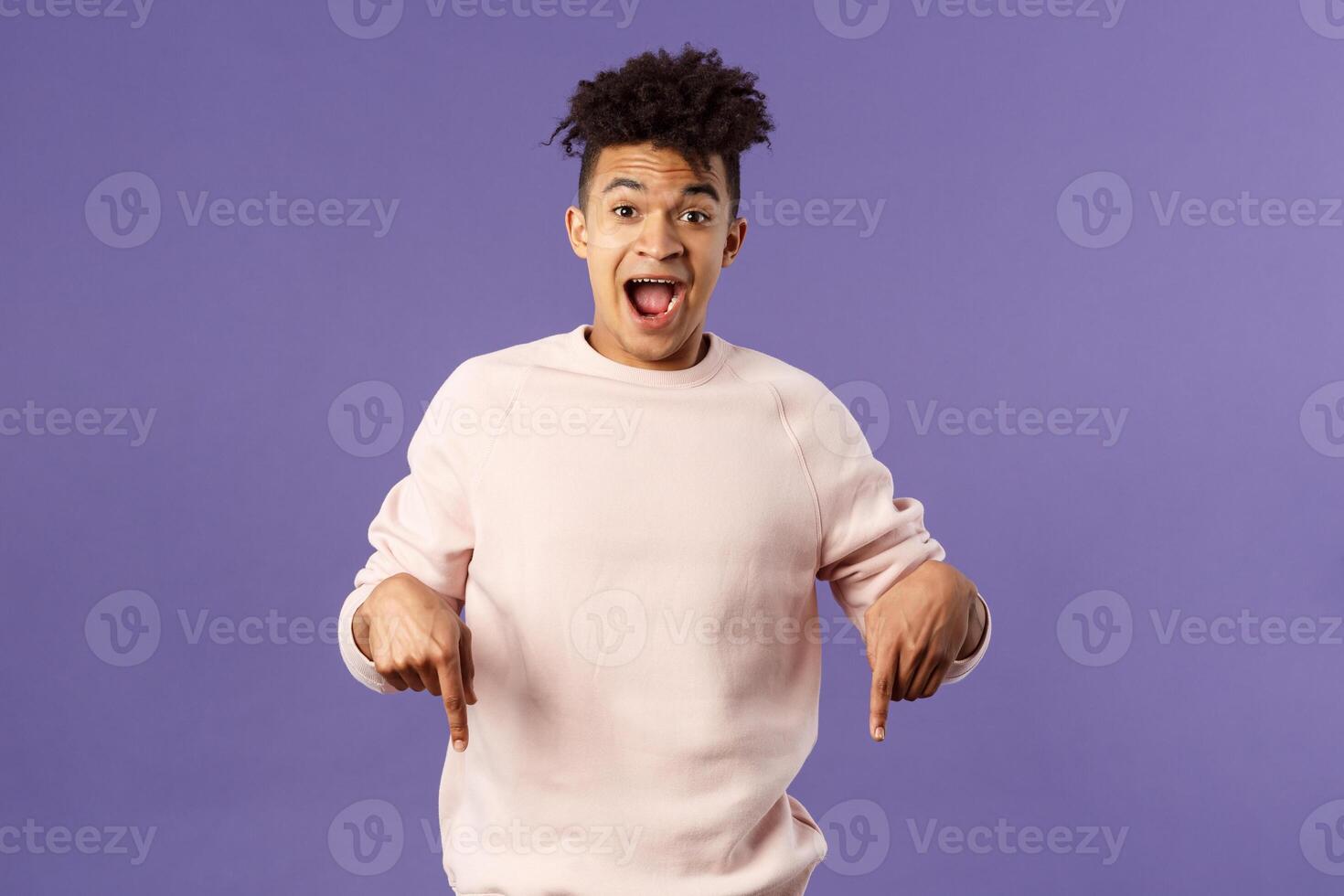 Portrait of handsome charismatic hispanic man inviting to subscribe, join courses or get this product right now, pointing fingers down, look camera fascinated and impressed, recommend promo photo