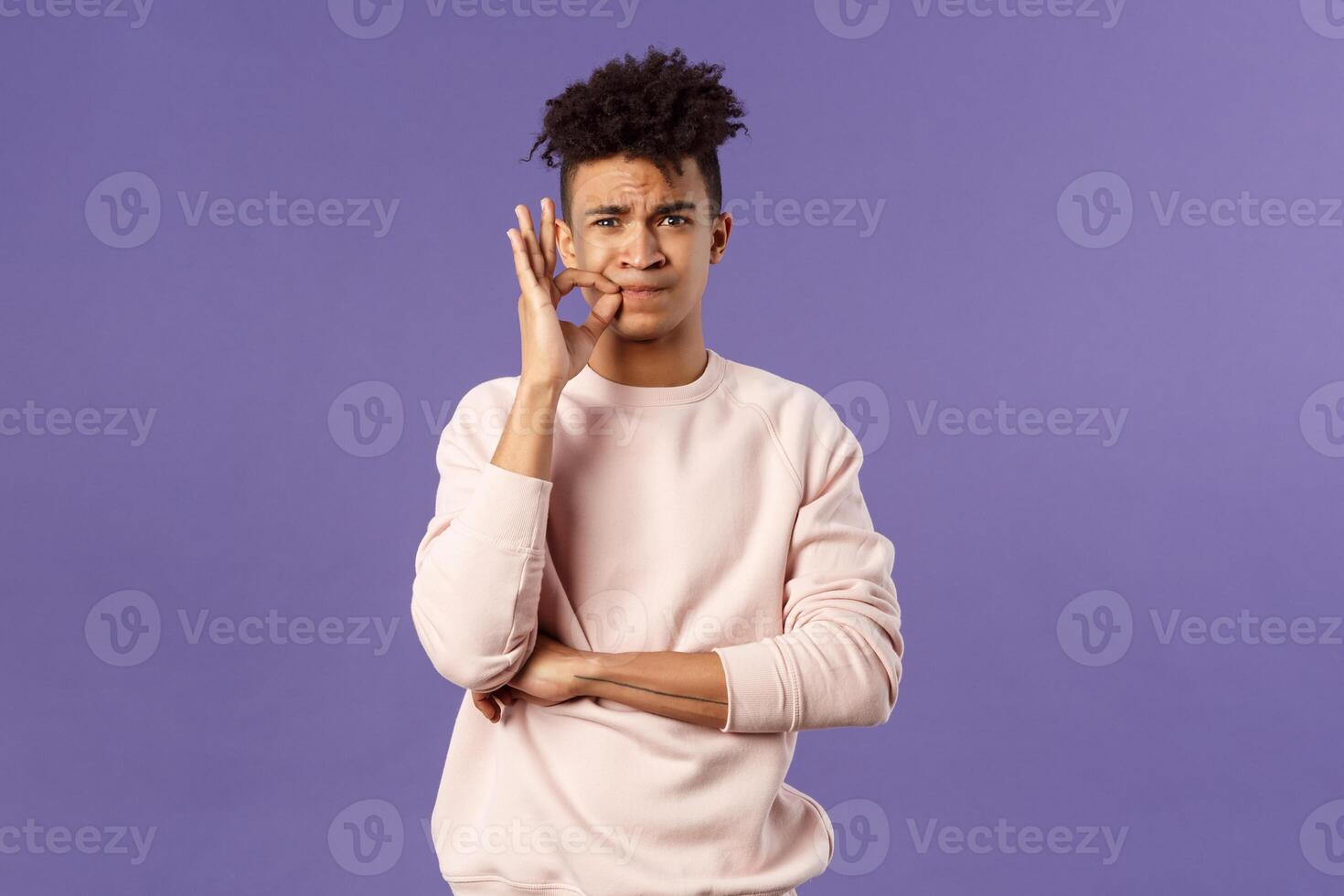 Portrait of serious-looking hispanic 25s young man promise to keep his mouth shut, secret is safe, zip his lips, lock it on key, hiding something cause he swear, standing purple background photo