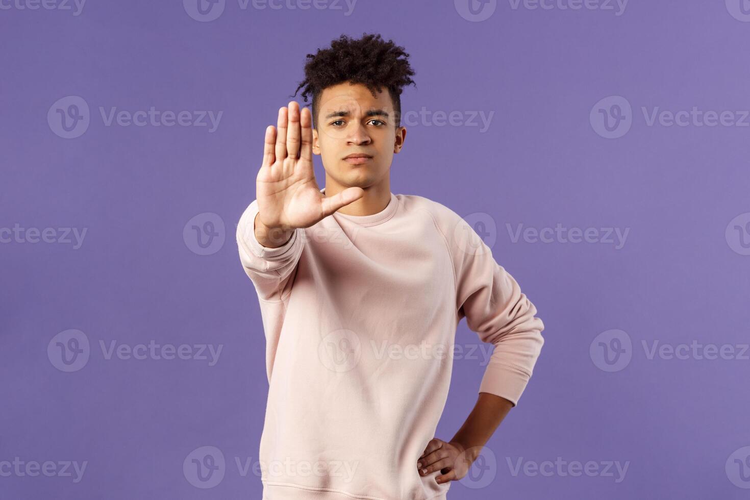 Portrait of confident serious-looking determined young man trying to prevent something, pull hand in stop gesture, look camera assertive, prohibit, give warning or forbid something photo