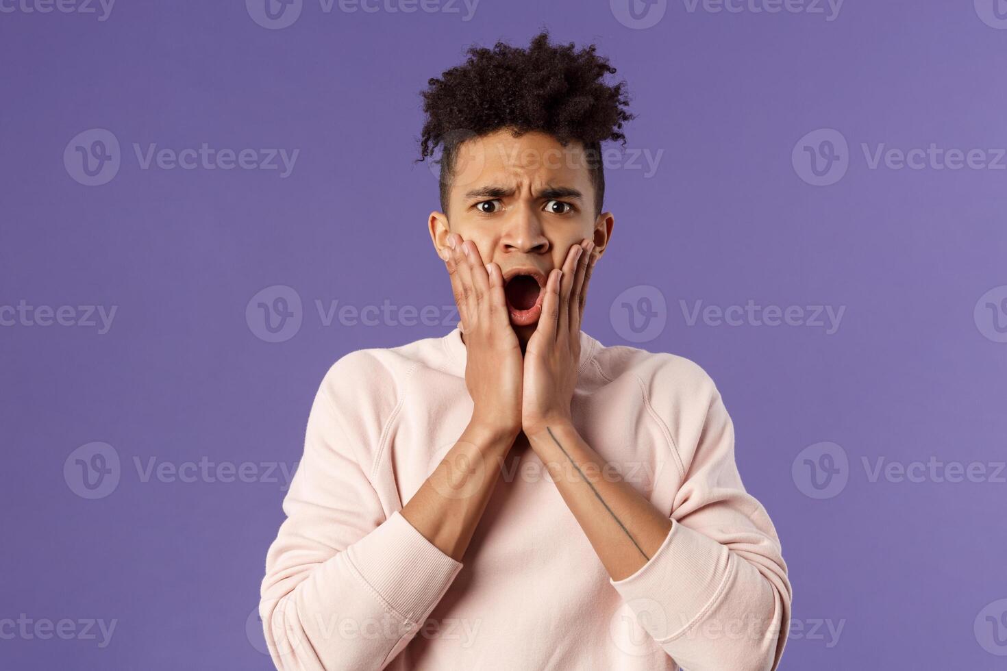 Oh gosh thats terrible. Portrait of shocked, speechless and worried young man express compassion finding out friend got in trouble, gasping open mouth and stare startled camera, touch face in shook photo