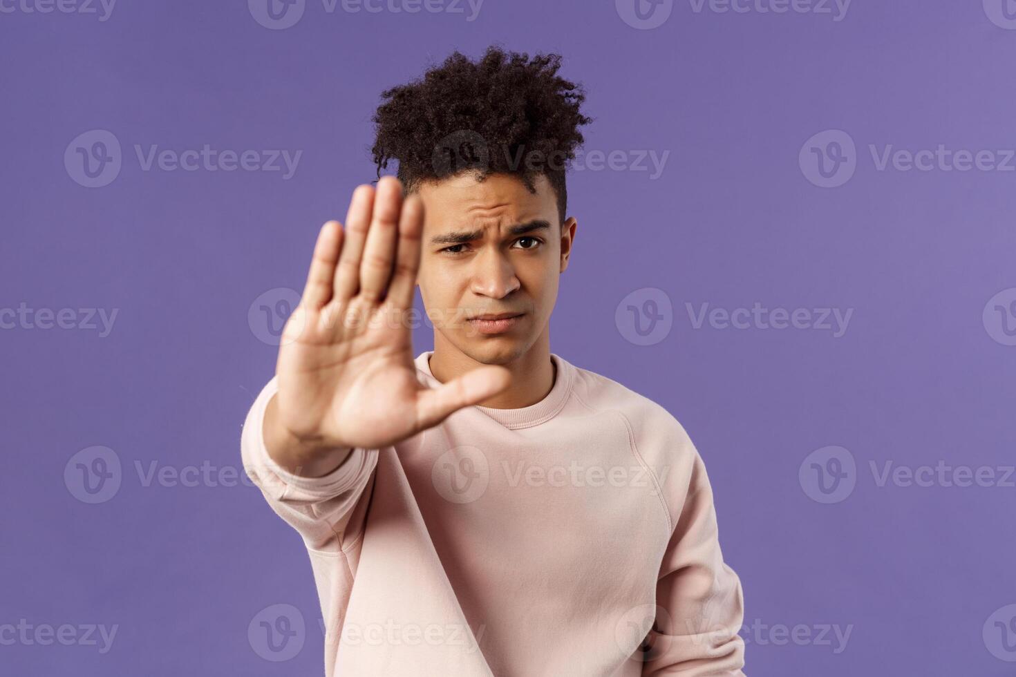 Man you should stop. Close-up portrait of young serious-looking male friend trying to warn person of doing something bad, raise hand to prohibit, forbid no trespassing, purple background photo