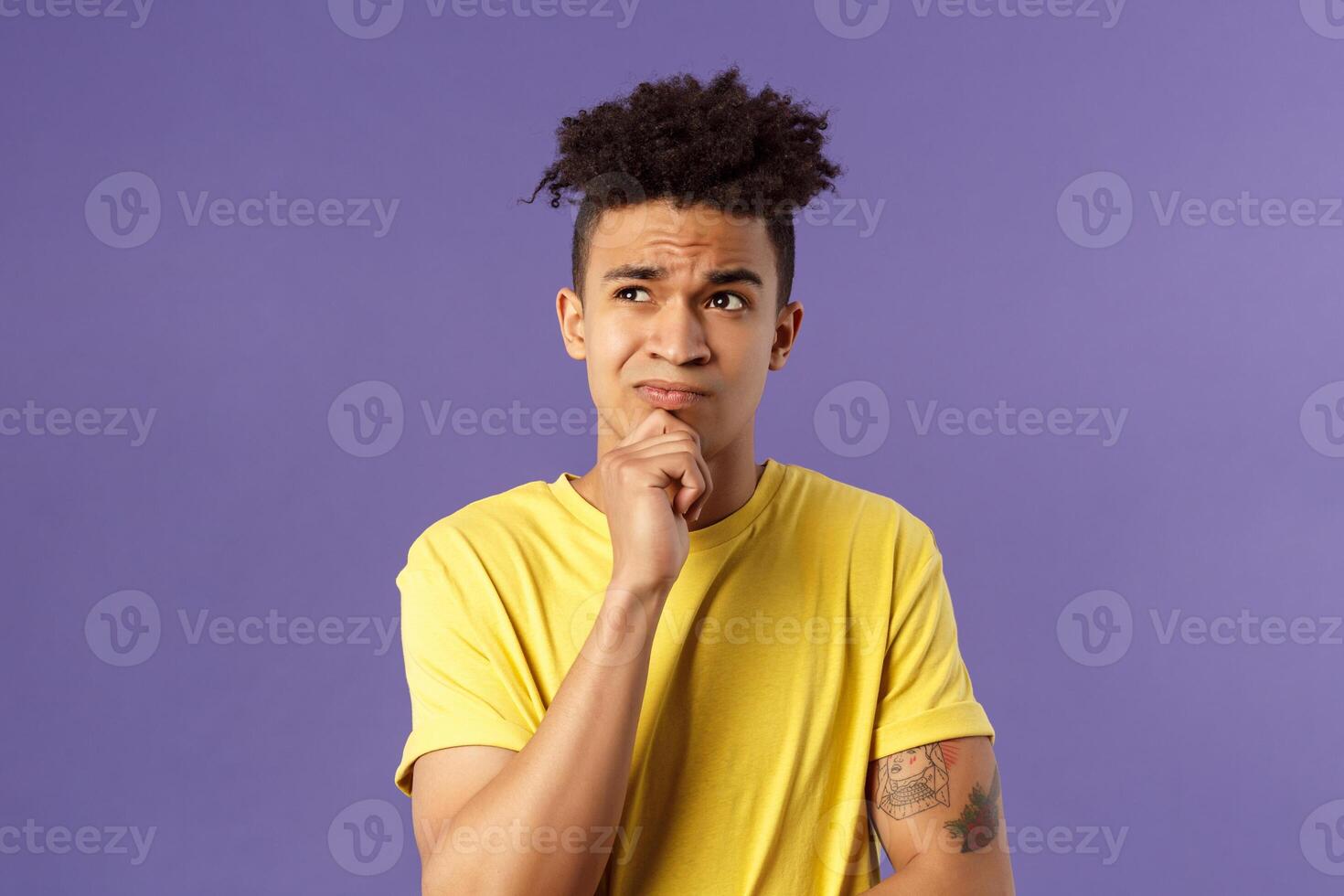 Close-up portrait of indecisive, puzzled attractive young man have problems, lacking idea, thinking, look away frowning and grimacing troubled, standing thoughtful purple background photo