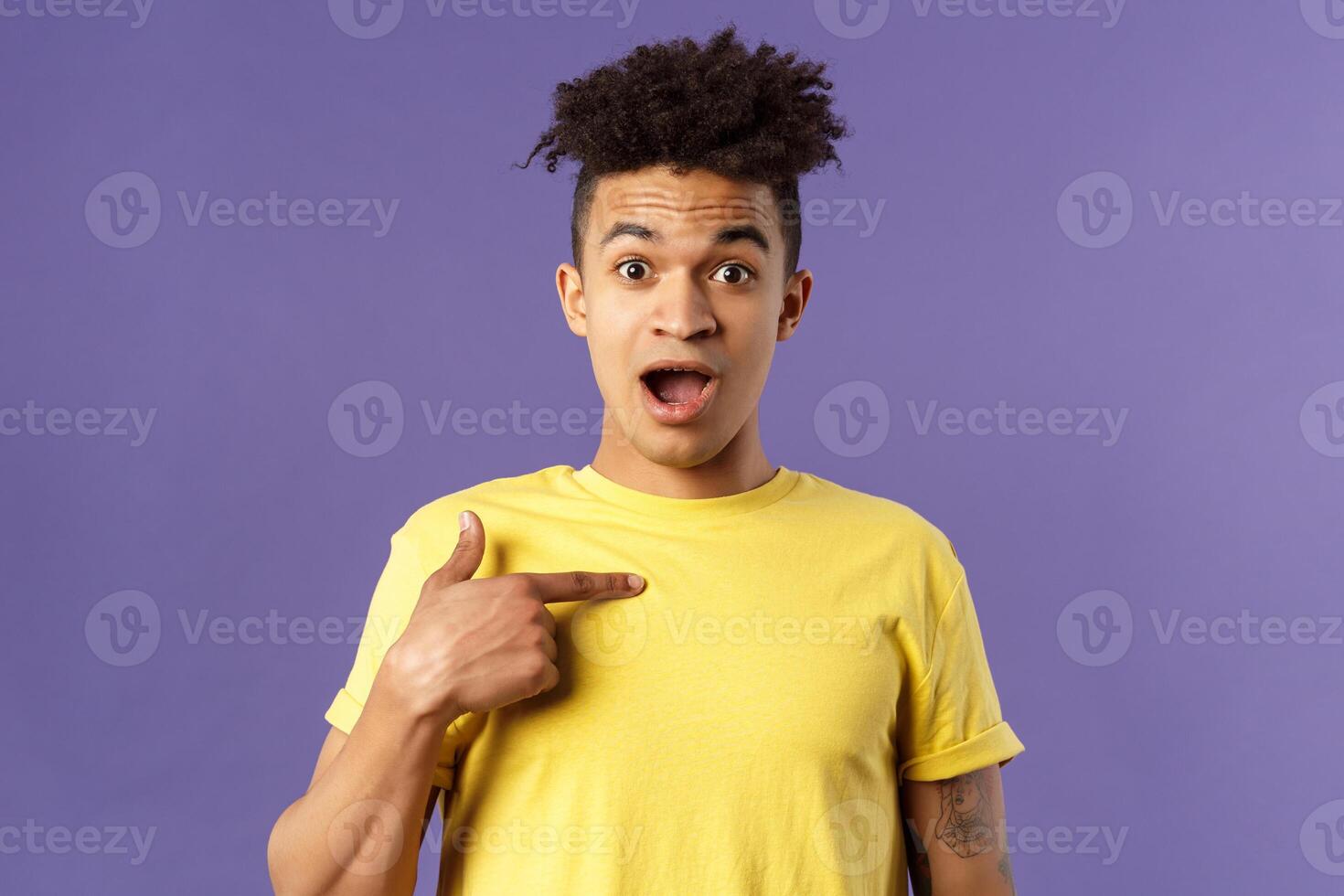 Who me, no way. Portrait of surprised, happy rejoicing young man looking with disbelies as being chosen from all candidates, pointing at himself open mouth fascinated, purple background photo