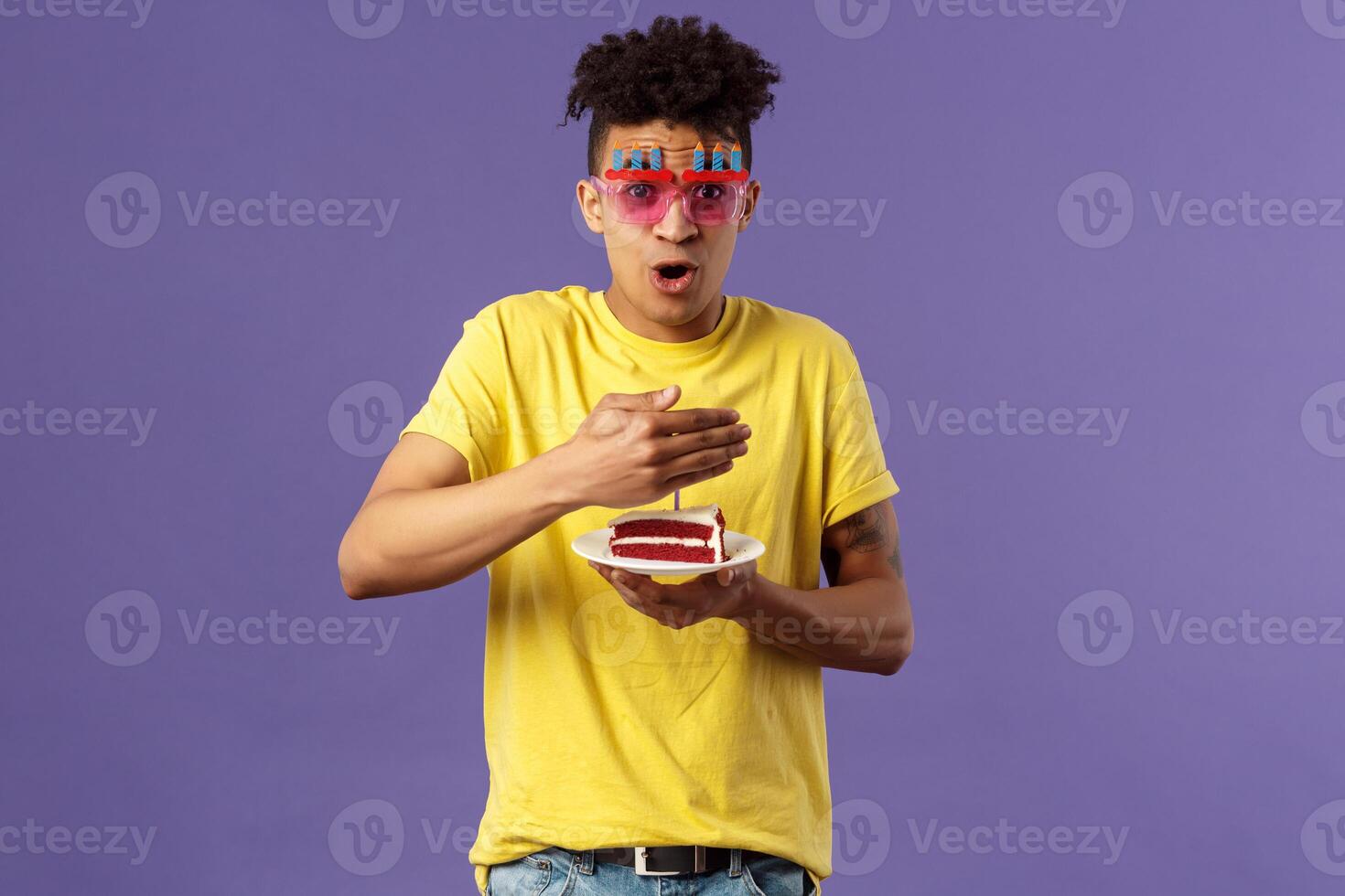 Celebration, party and holidays concept. Portrait of happy funny, enthusiastic young man celebrating birthday, protect lit candle on b-day cake from wind, making wish, smiling cheerful photo