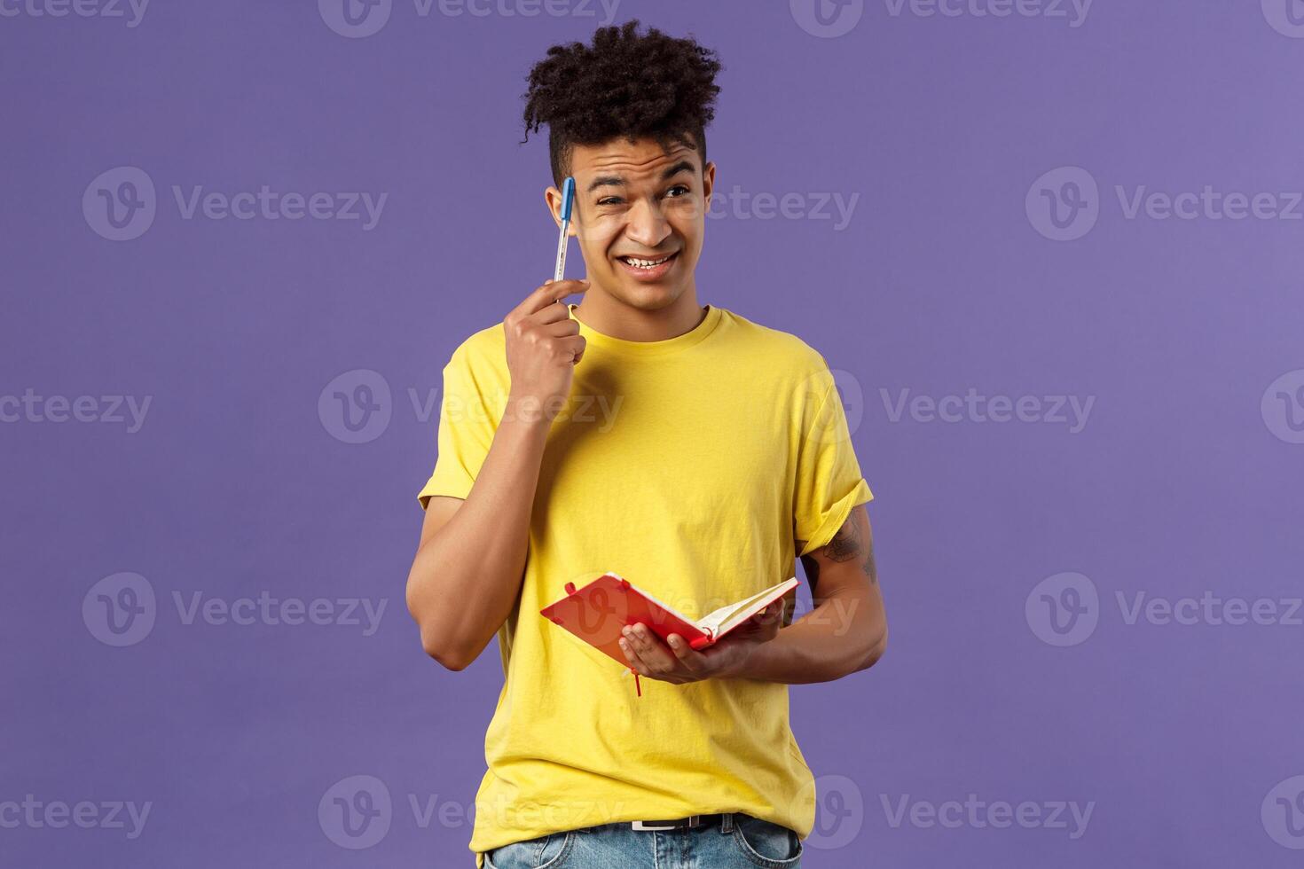Young troubled male student studying, doing homework, scratch head indecisive and unsure, facing complicated task, dont know how solve equation, grimacing, holding notebook, thinking photo