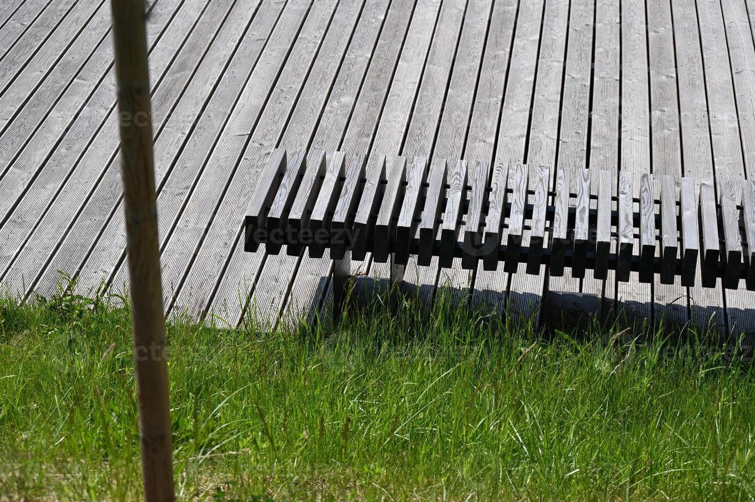 a bench sitting in the grass next to a wooden deck photo