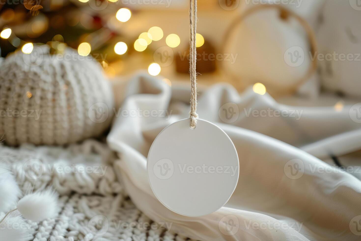 White blank round flat ceramic ornament tag with ribbon hanging in soft boho setup photo