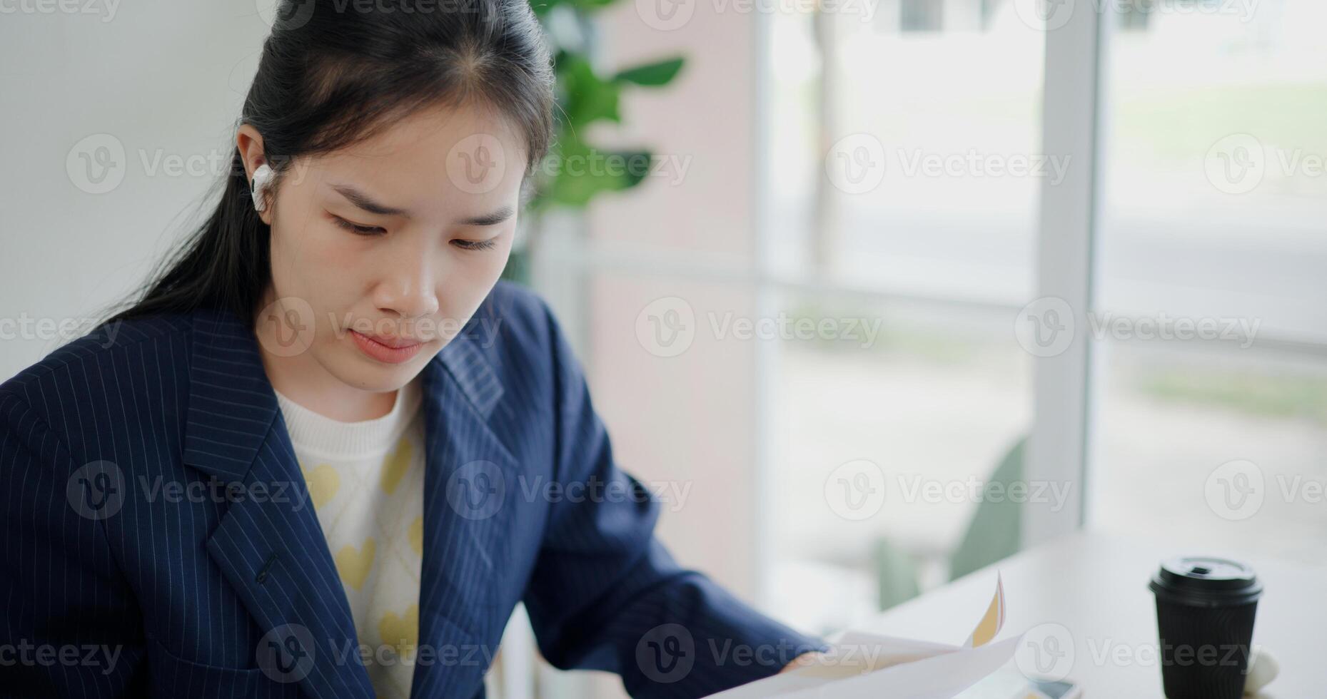 Portrait of Asian businesswoman in suit use digital tablet for work and analyze documents in small coffee shop. Work from anywhere, Remote working photo