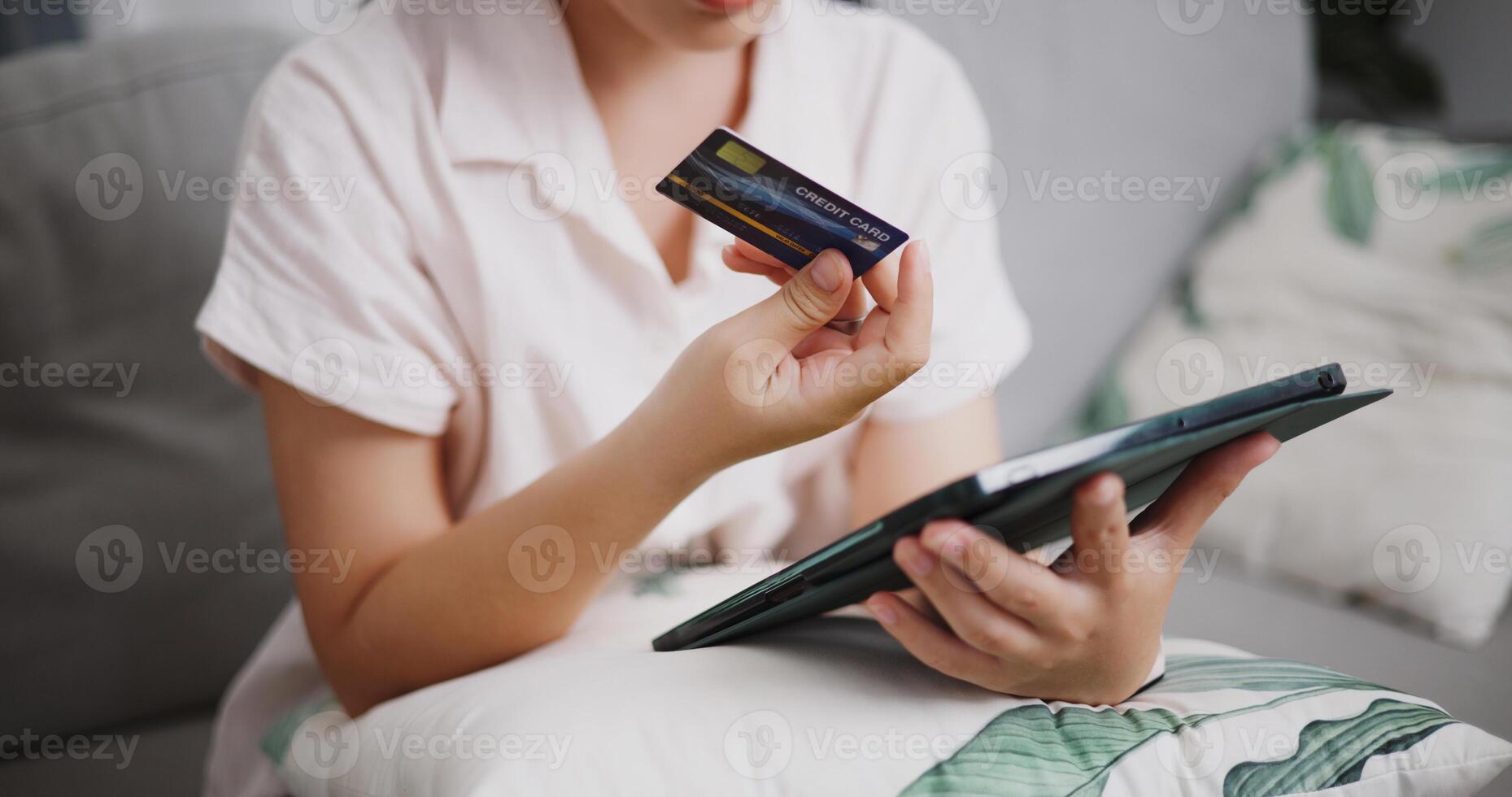 Selective focus, Hands of young woman using credit card to pay on digital tablet in the living room at home ,Buy things online by tablet, Pay online. photo