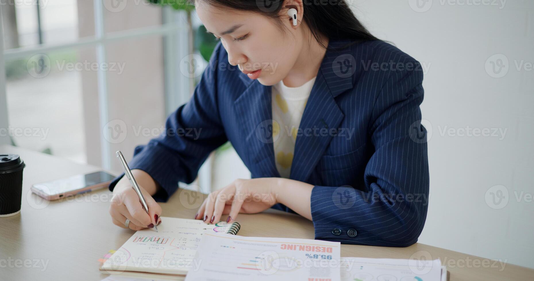 High angle view, Asian businesswoman in suit sits on table while analyze documents and taking notes in small coffee shop. Work from anywhere, Remote working photo