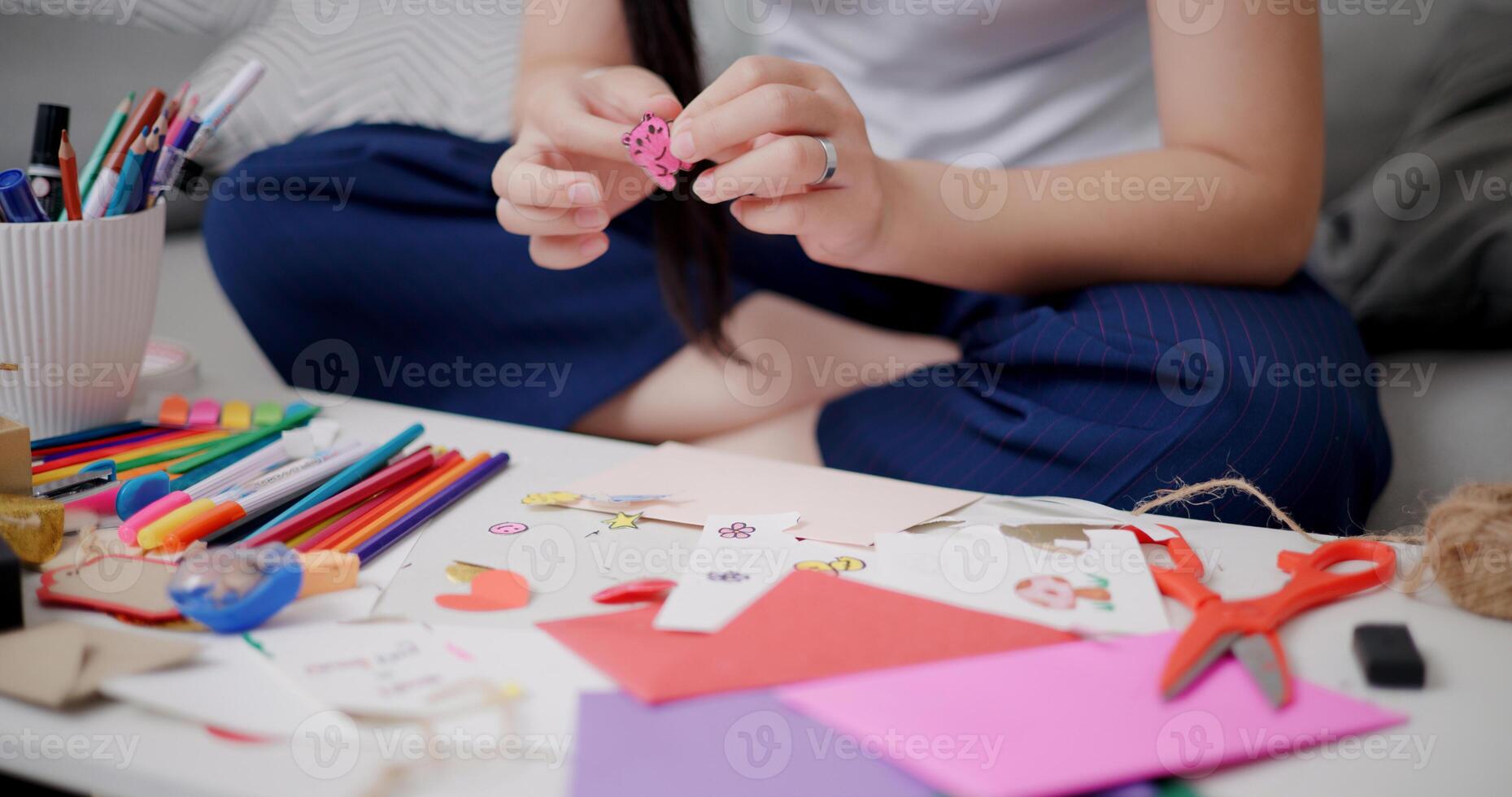 Selective focus, Hands of Young Asian woman sitting on sofa decorating a greeting card in the living room, Holiday hobbies, crafts, DIY cards photo