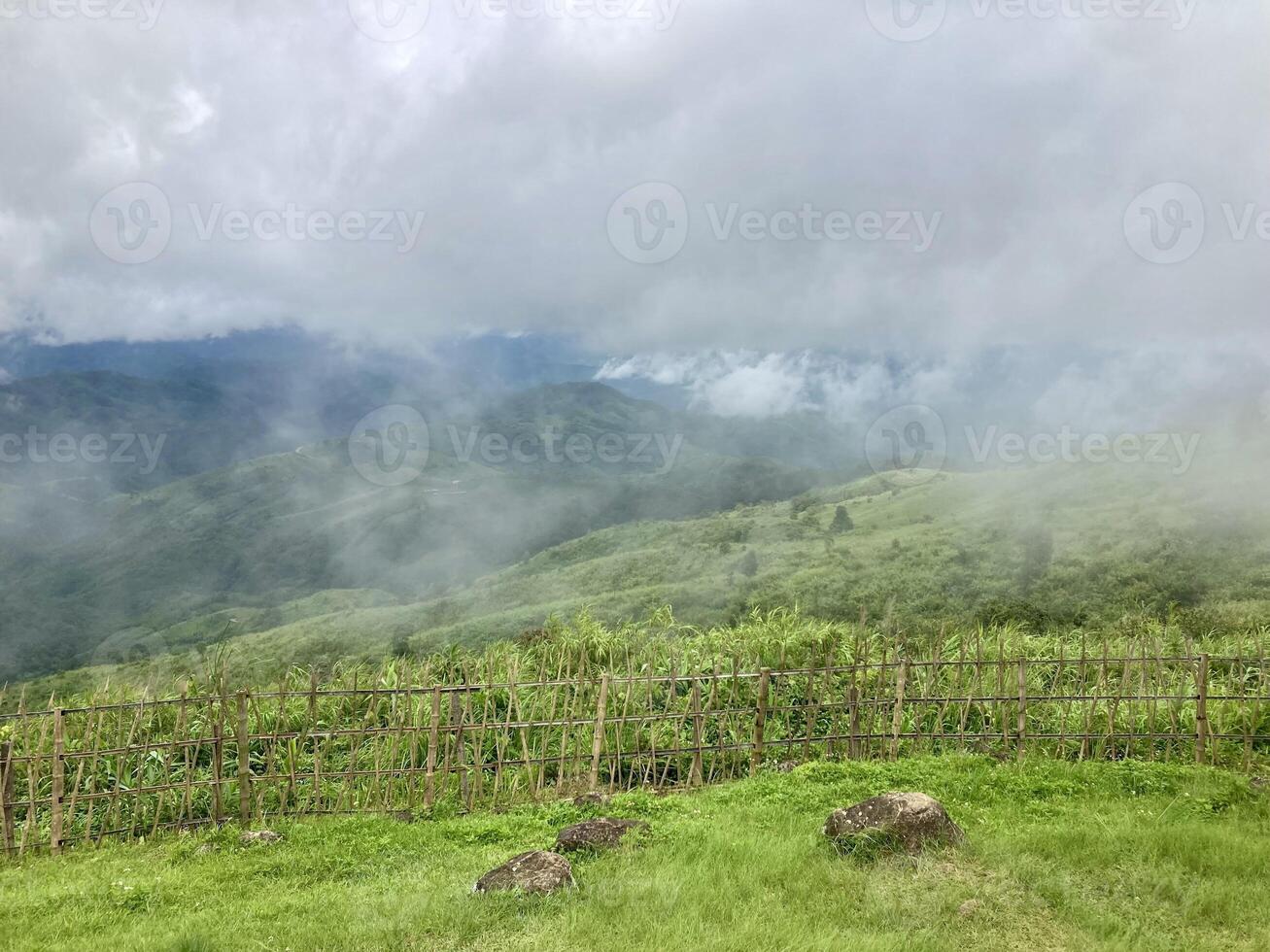 The mist flows through the mountain forest, Sun shining into tropical forest, Mist drifts through mountain ridges in the morning, slow floating fog blowing cover on the top of mountain photo