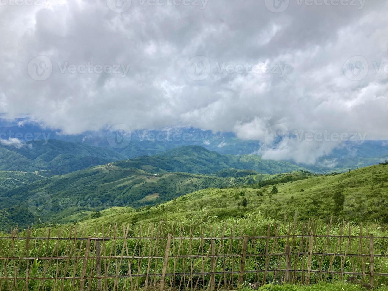The mist flows through the mountain forest, Sun shining into tropical forest, Mist drifts through mountain ridges in the morning, slow floating fog blowing cover on the top of mountain photo