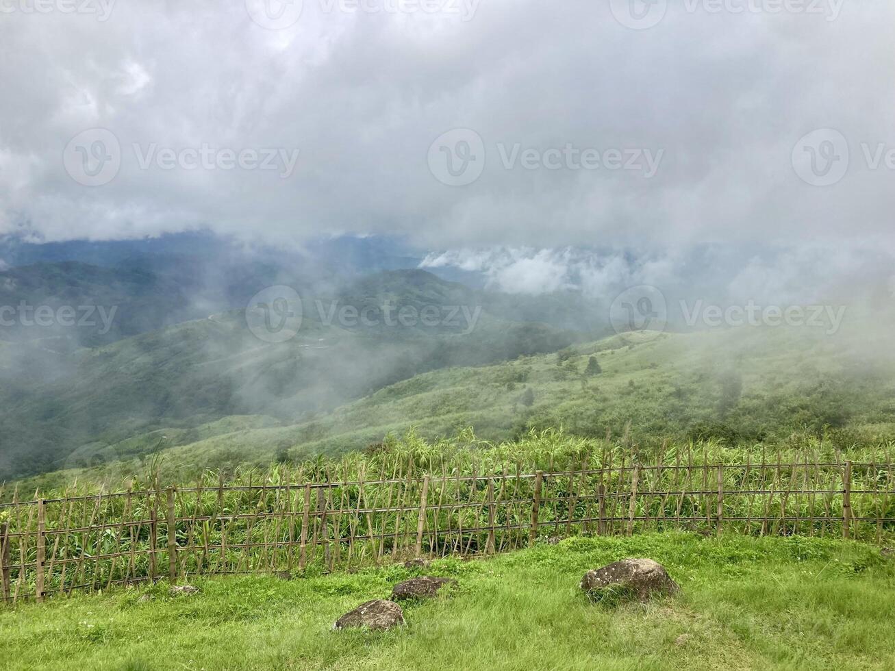 The mist flows through the mountain forest, Sun shining into tropical forest, Mist drifts through mountain ridges in the morning, slow floating fog blowing cover on the top of mountain photo