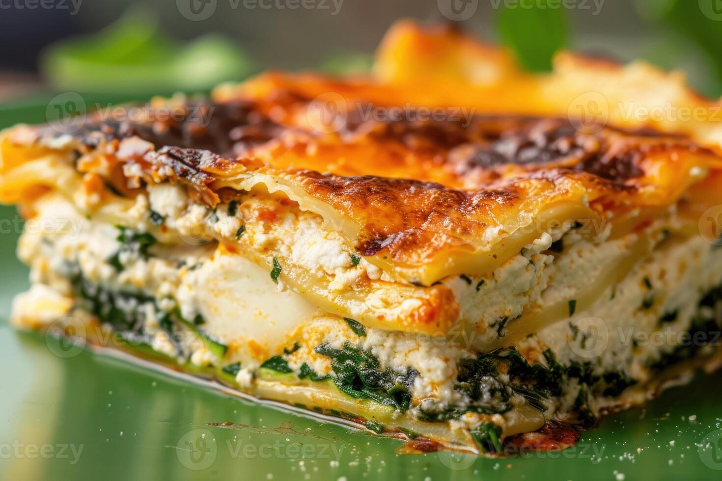 An enticing slice of vegetarian lasagna sits on a green plate, showcasing layers of cheese, spinach, and pasta, inviting a delicious culinary experience. photo
