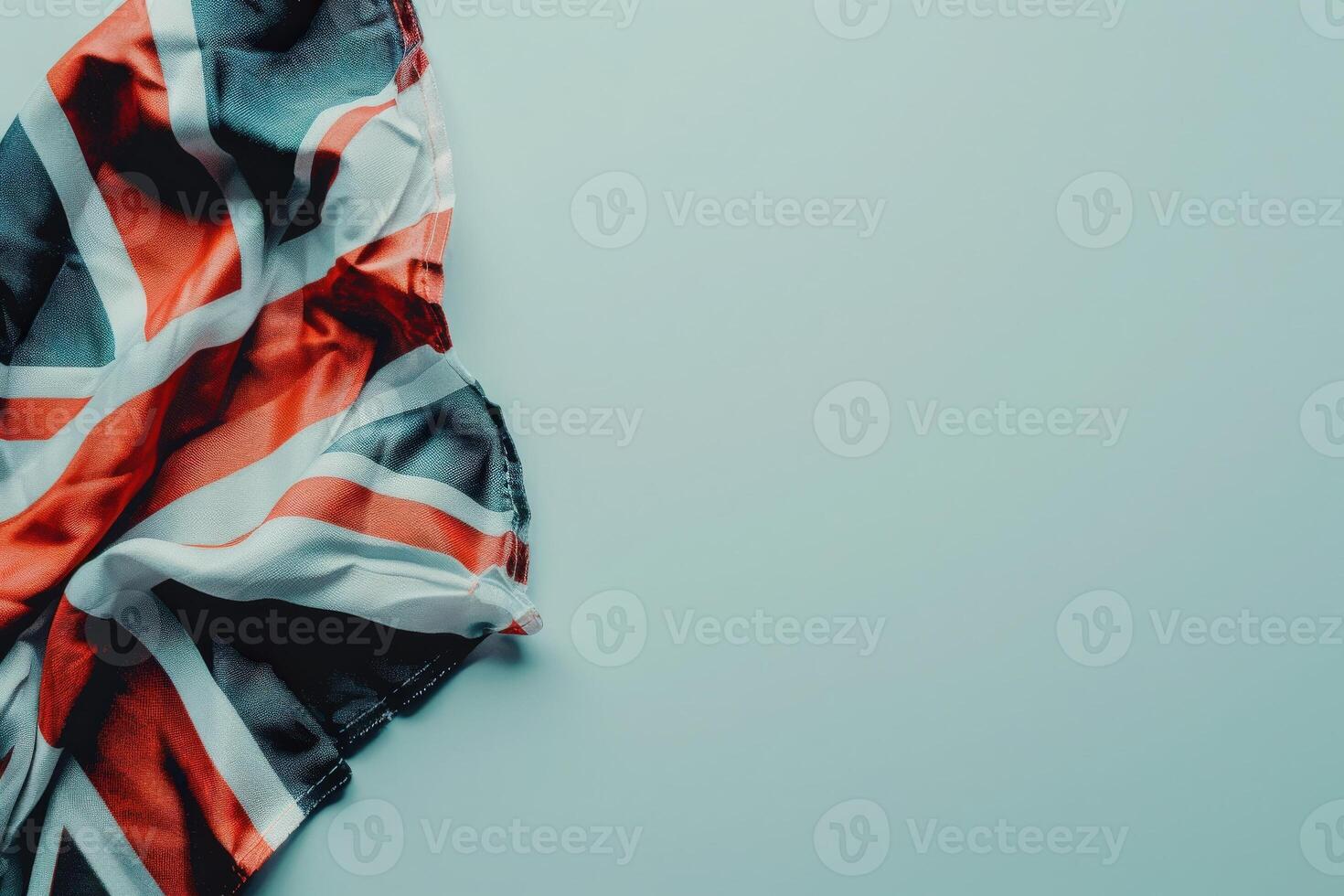 A neatly folded Union Jack flag rests on a smooth white background, displaying its vibrant red, white, and blue colors in a serene arrangement. photo