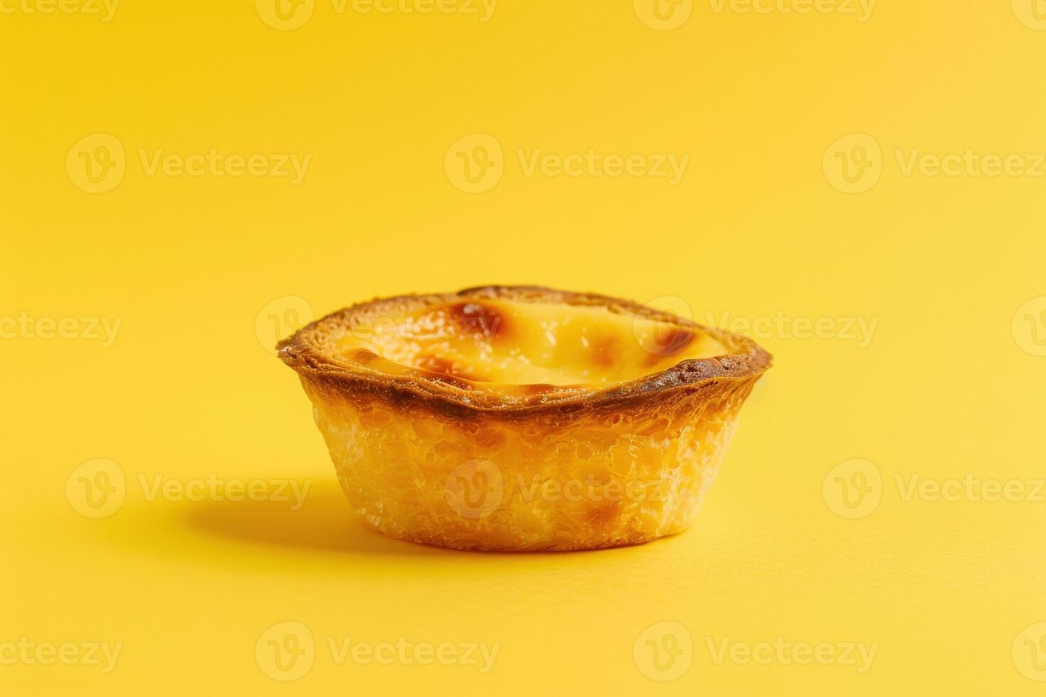 A scrumptious pastel de nata sits alone against a vibrant pastel yellow backdrop, showcasing its flaky crust and creamy filling. photo