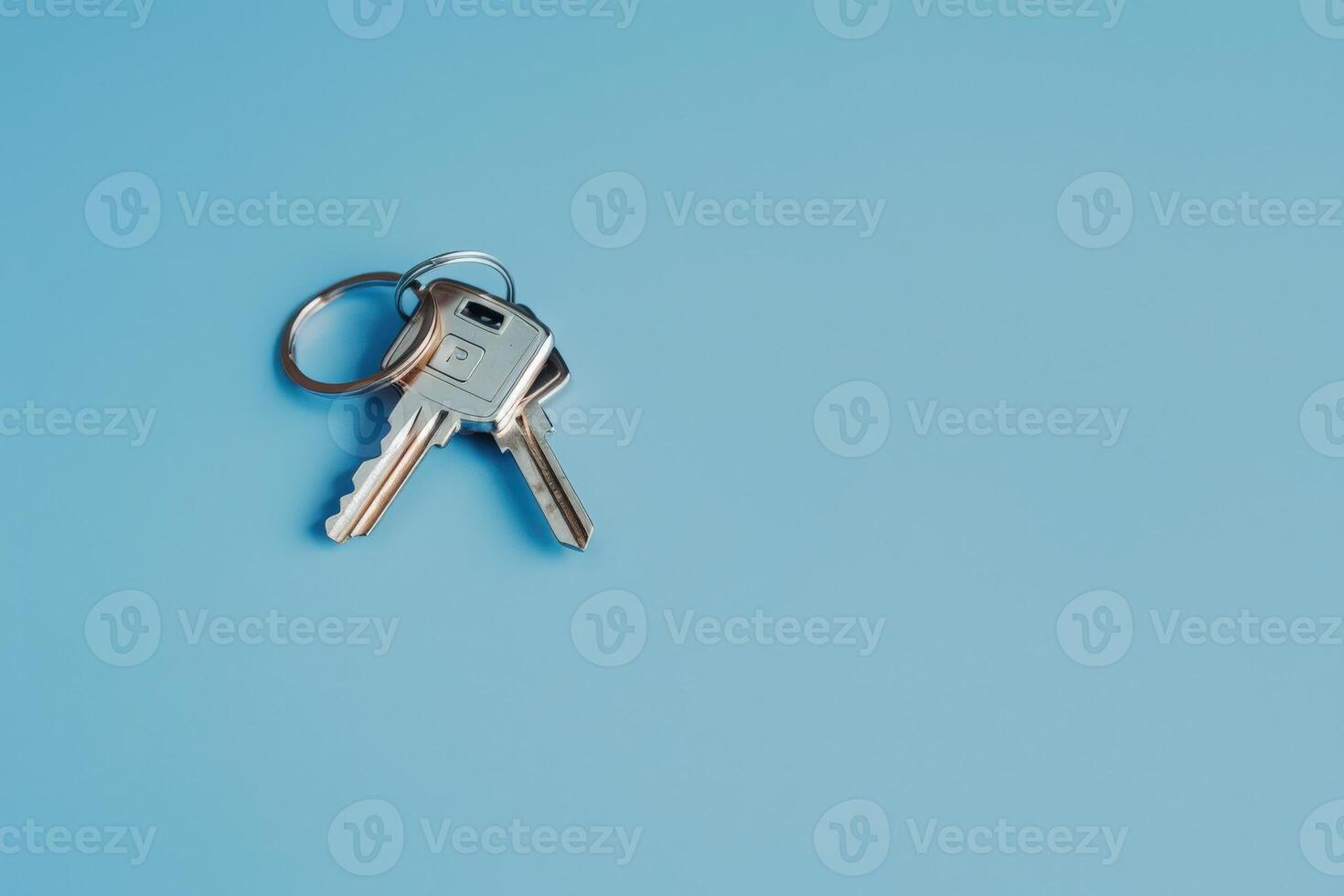 A sleek set of car keys glimmers under soft light, isolated against a serene blue background, showcasing modern design. photo