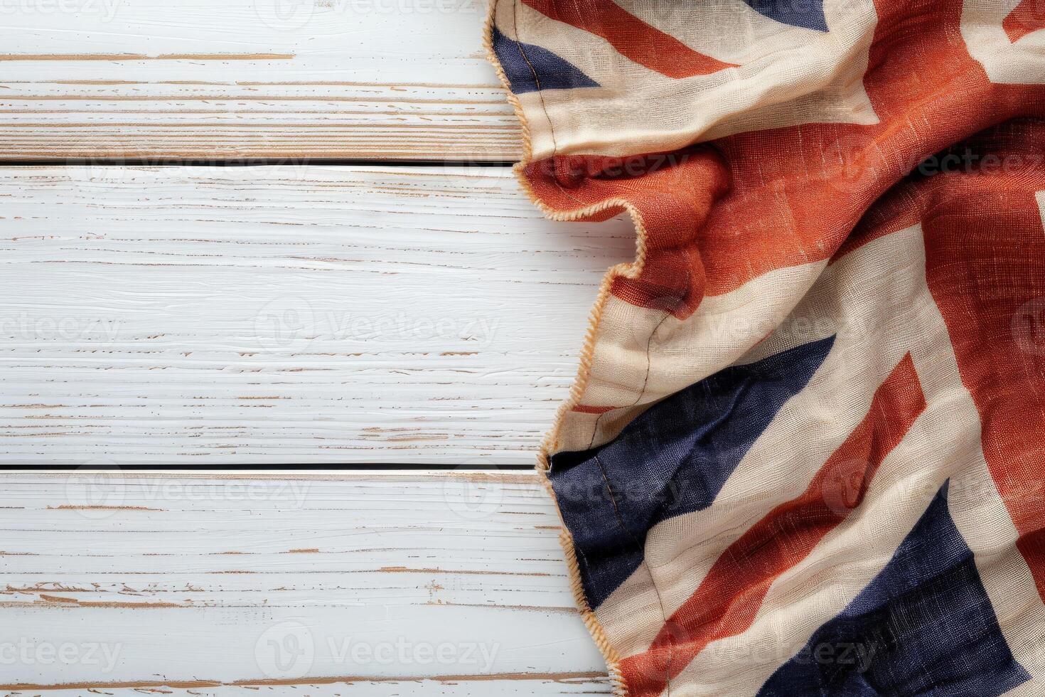 The Union Jack flag is gracefully folded, showcasing its vibrant colors against a textured white wooden backdrop, evoking a sense of national pride. photo