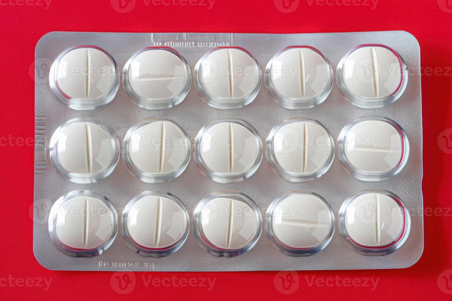 An isolated blister pack containing white pills is prominently displayed against a striking red surface, creating a compelling visual contrast. photo