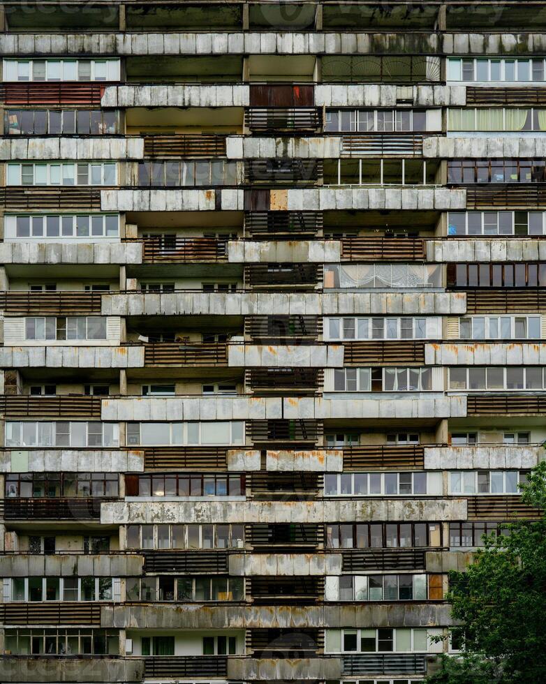 Facade of an old multi-storey residential building with balconies. Rusty facing of balconies. Residential building in the slum. photo
