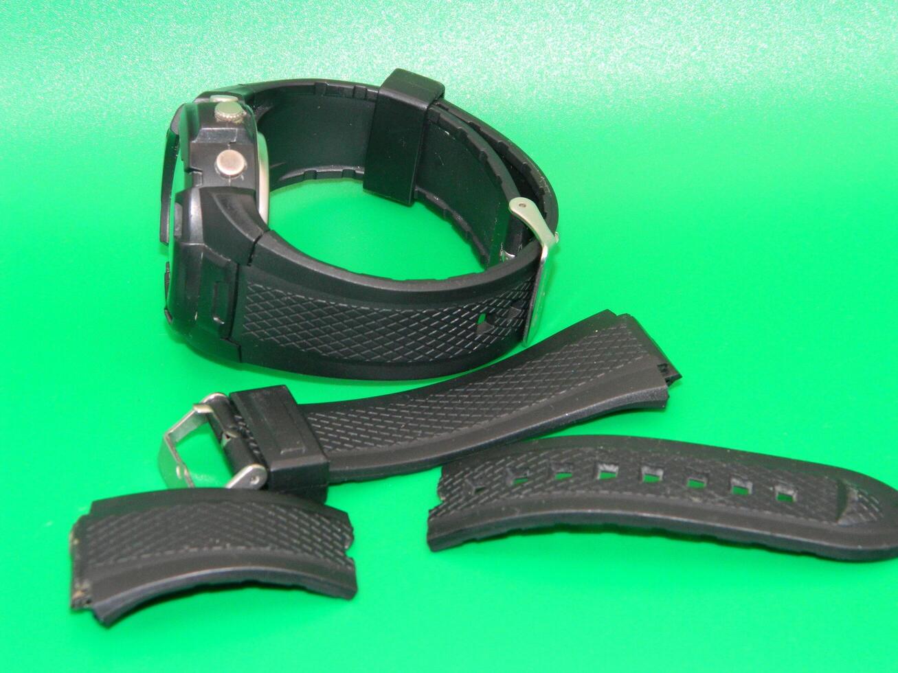 Photo of a damaged black watch strap on a green background
