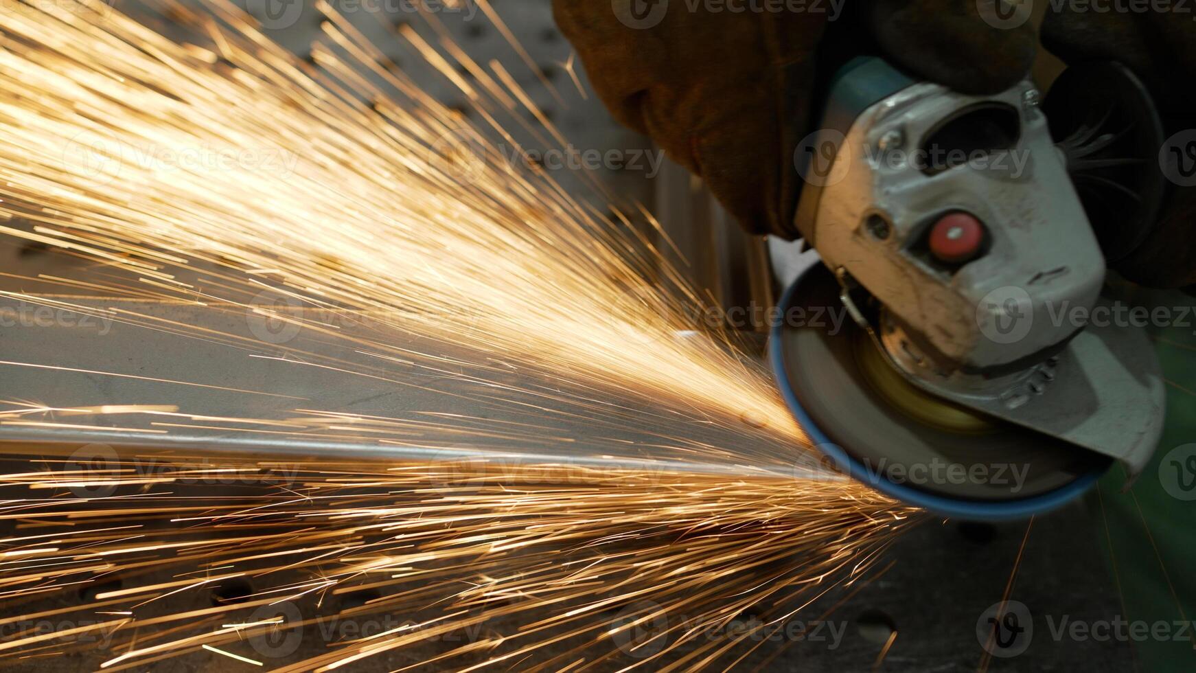 A worker cuts, grinds and polishes a metal part with sparks in a workshop, close-up. Metal grinding, close-up. A worker cuts metal with a grinder, bright red sparks close-up. photo