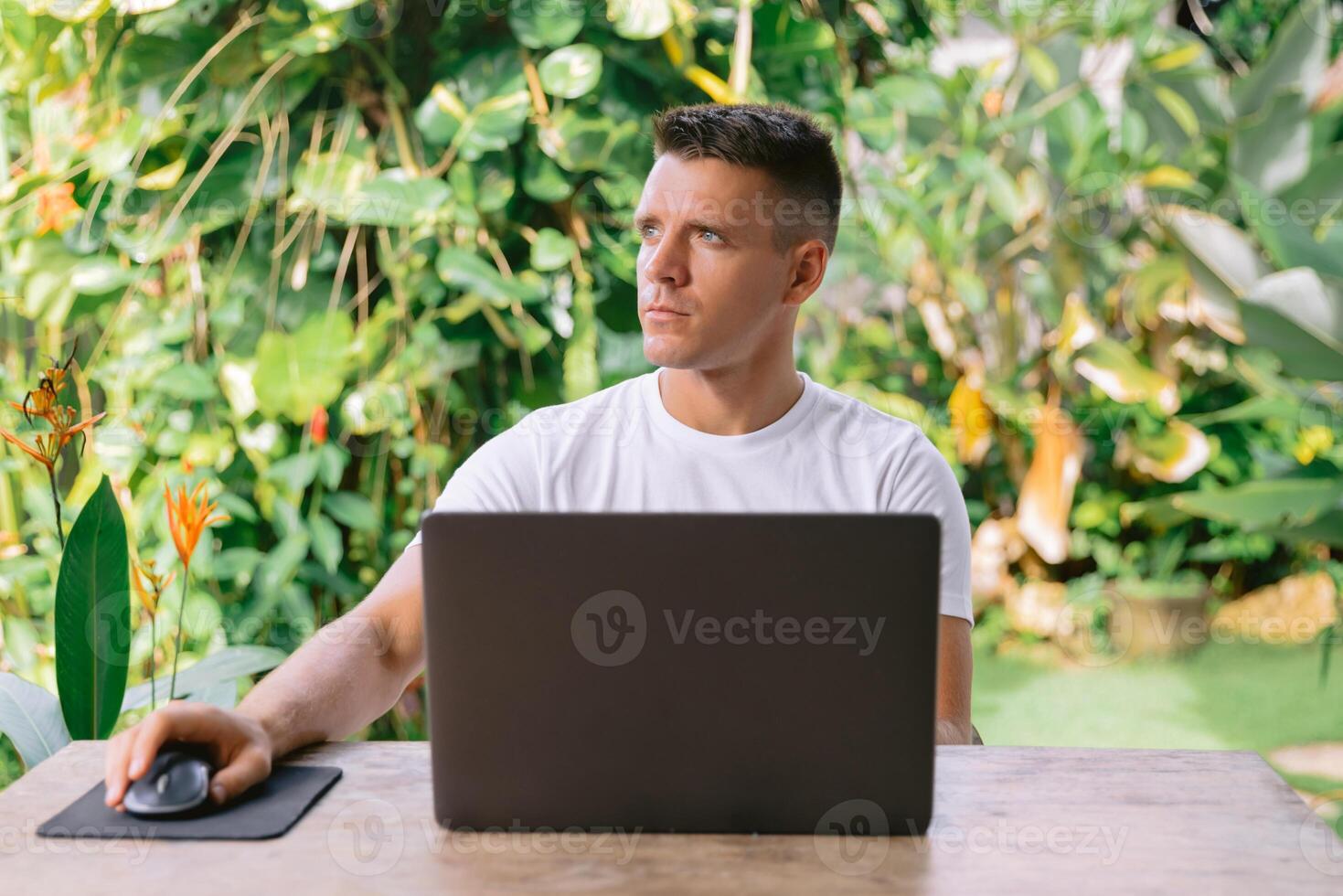Focused man thinking about new idea with laptop, successful freelancer working online on computer in summer cafe photo
