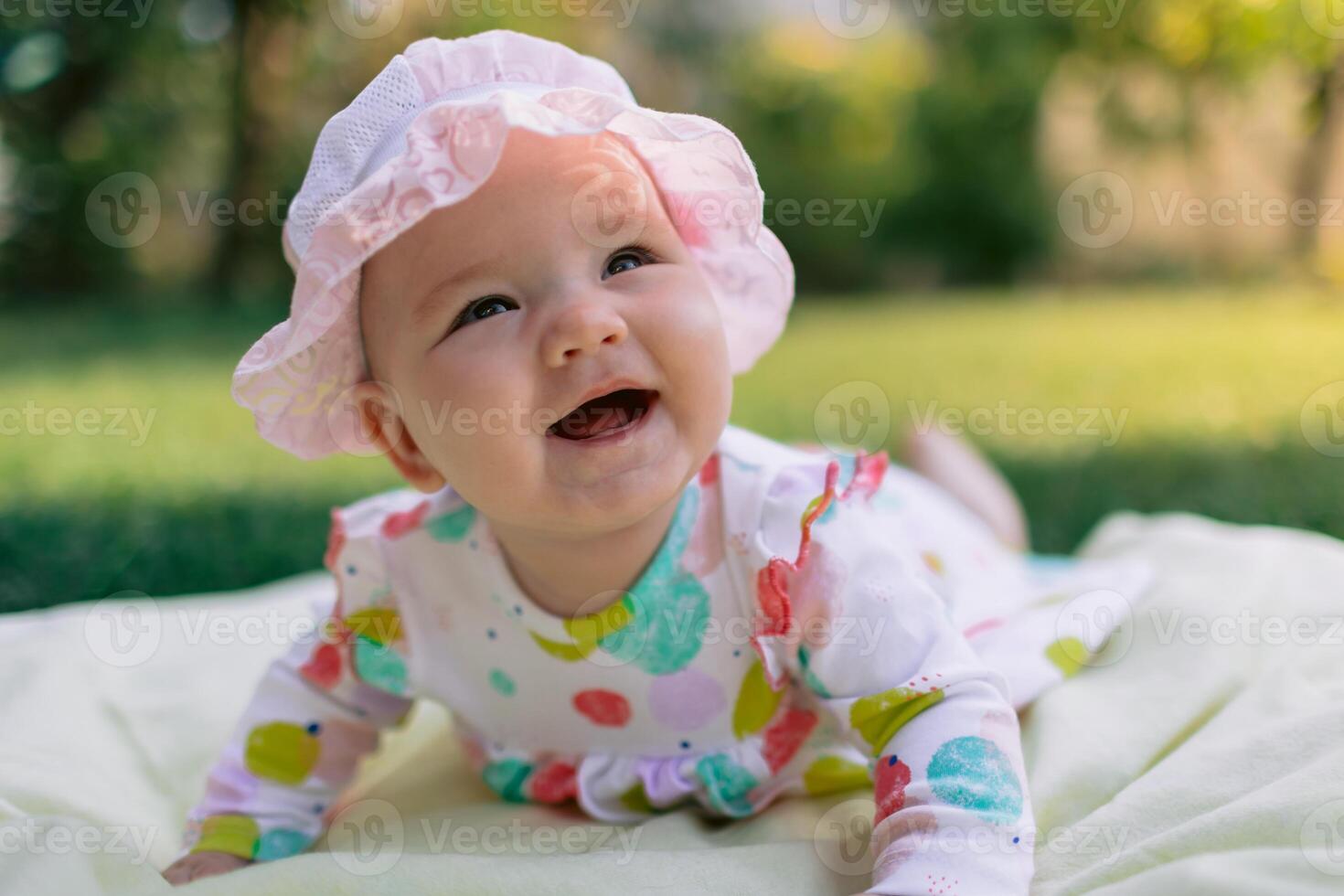 Smiling baby girl lay on the lawn in garden photo