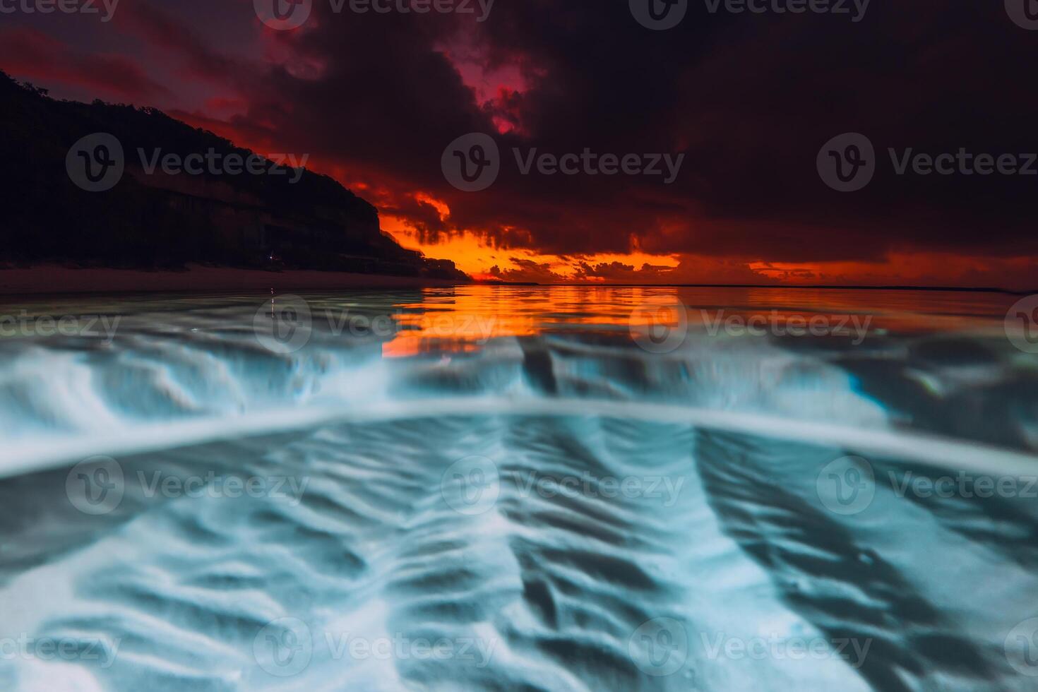 Split view with sunrise and underwater sandy sea bottom. photo