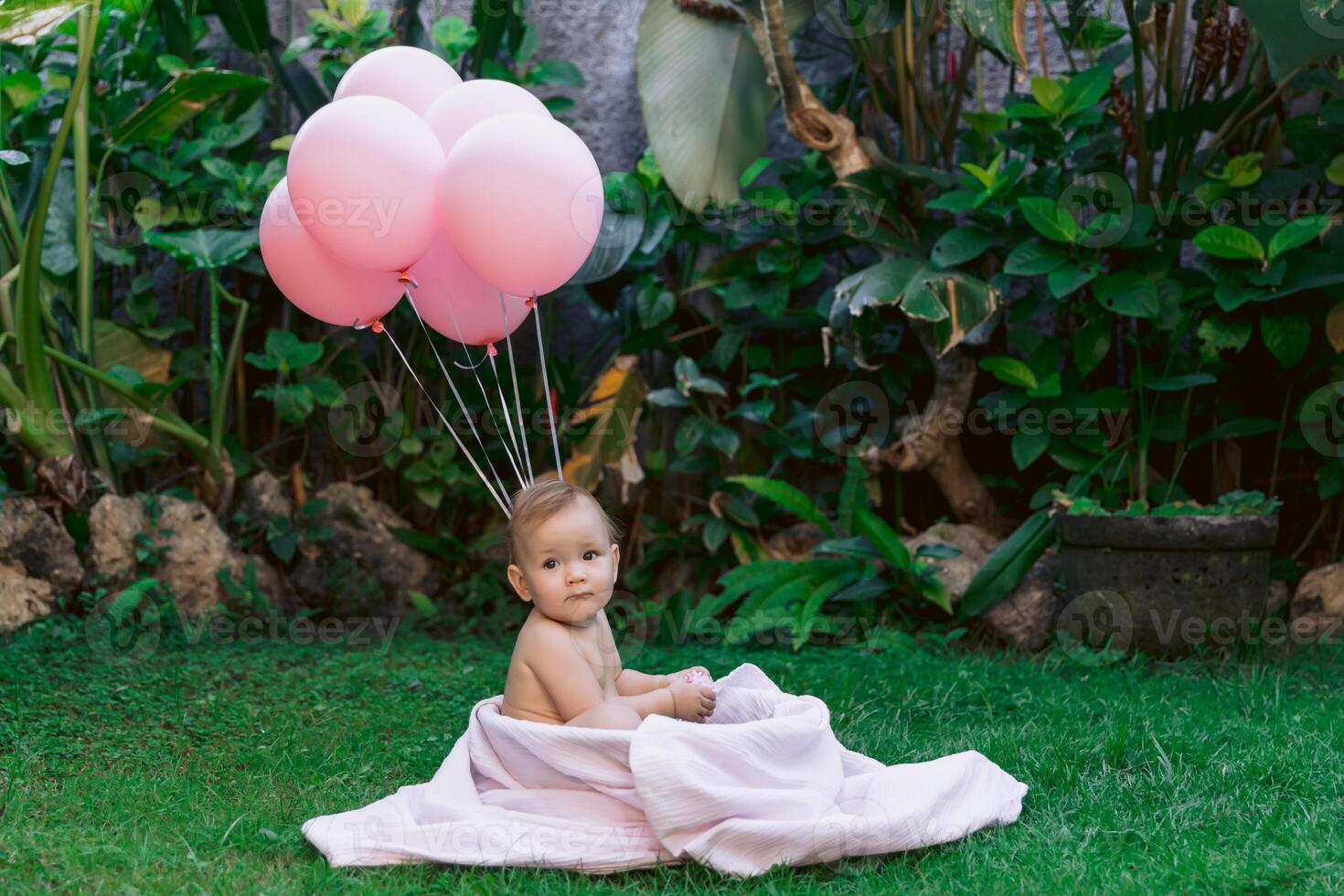 Baby girl and pink air balloons swim in baby bath outdoor garden. Happy baby. photo