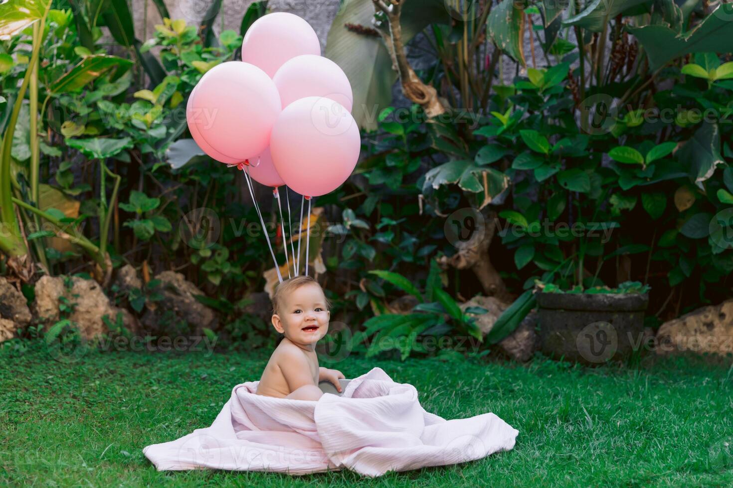 Smiling baby girl and pink air balloons swimming in baby bath outdoor summer garden. photo