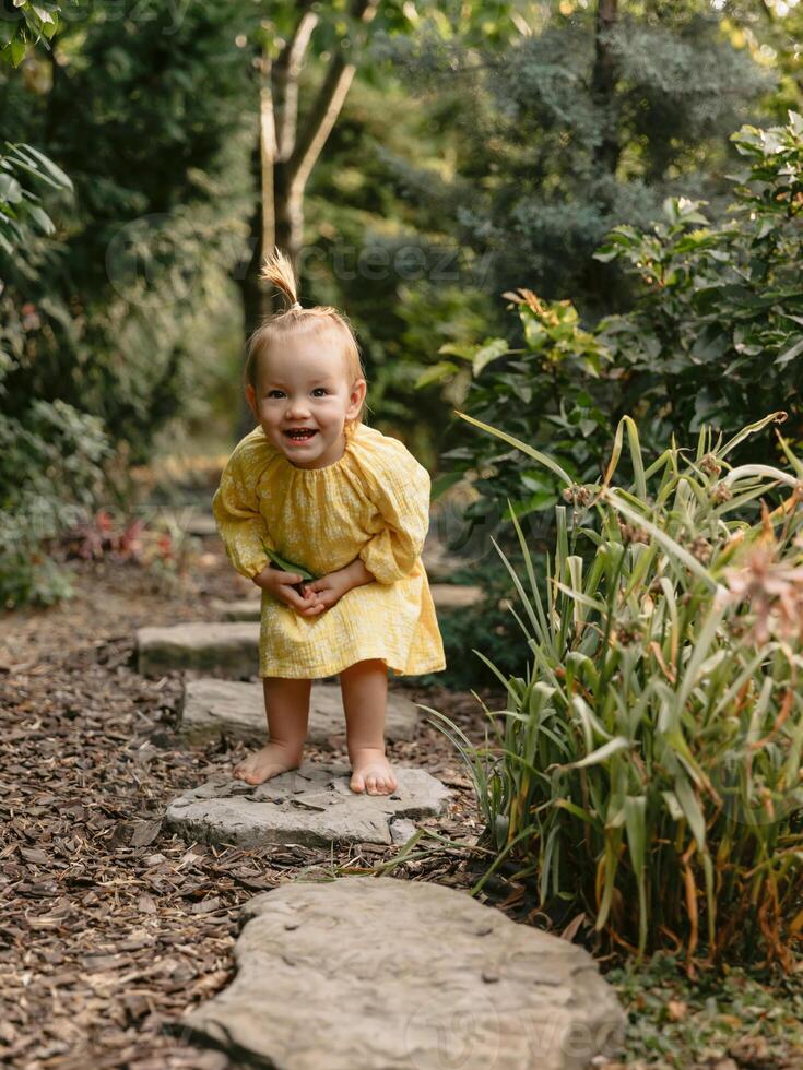 Smiling little girl in stylish dress in backyard garden. photo