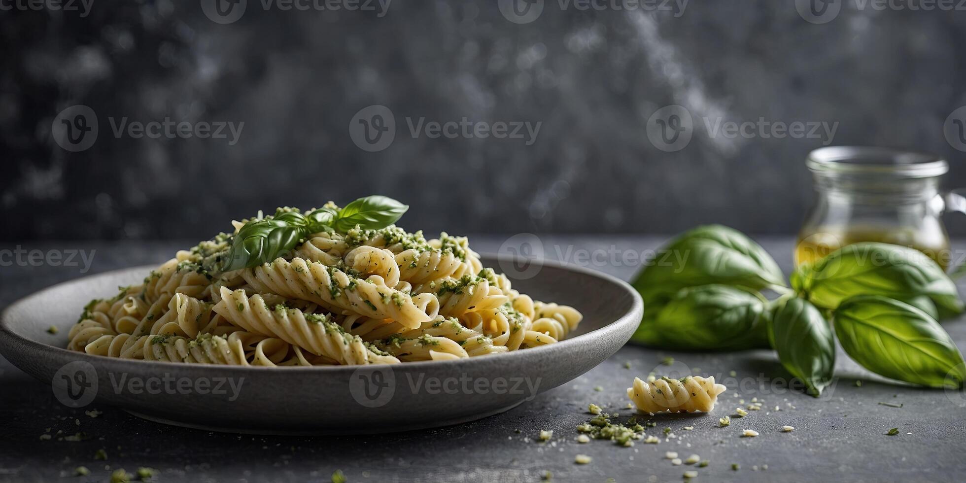 Italian homemade fussili pasta with basil pesto and herbs presented on a gray stone background offering a delightful and nutritious meal idea. photo