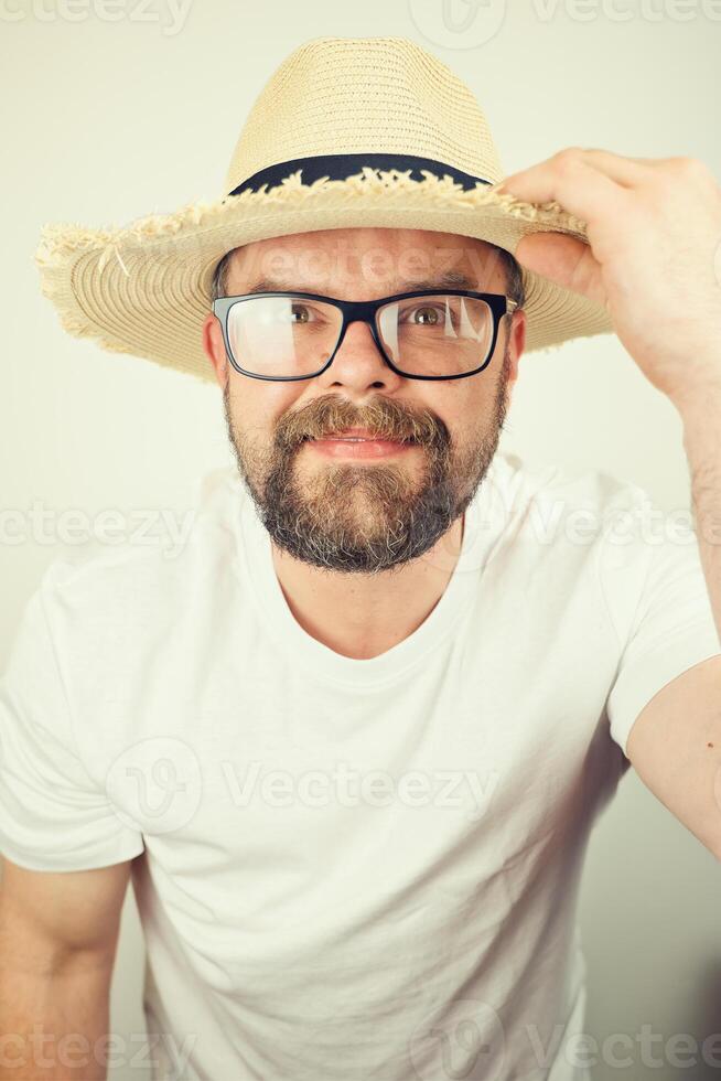 portrait of handsome bearded man with straw hat and glasses smiling, wearing white shirt , isolated on white background photo