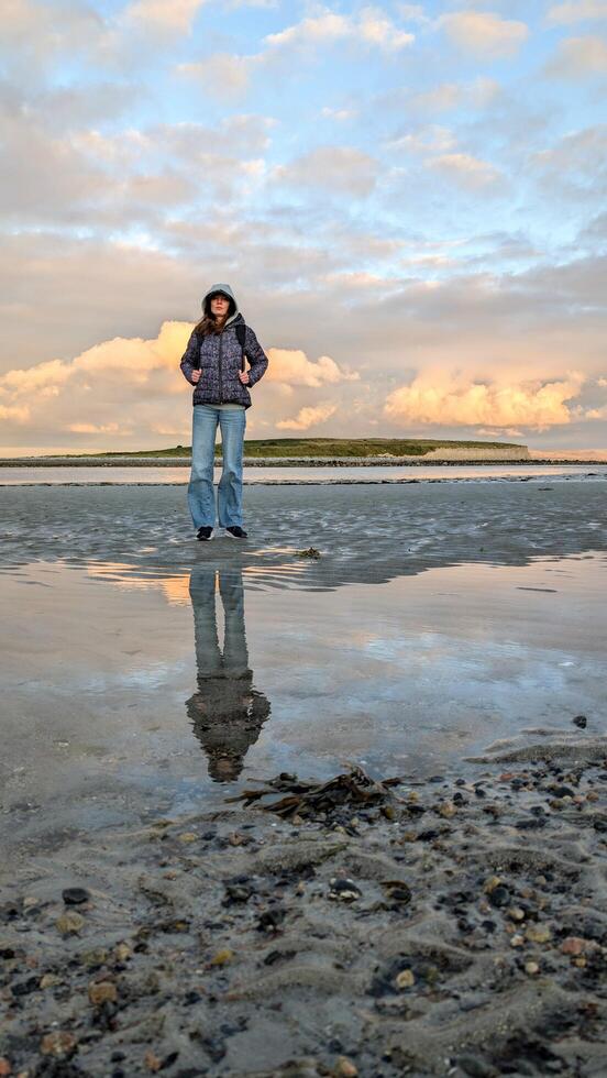 woman hiker backpacker enjoying coastal sunset scenery at sandy Silverstrand beach, Galway, Ireland, adventure and lifestyle concept, people in nature background photo
