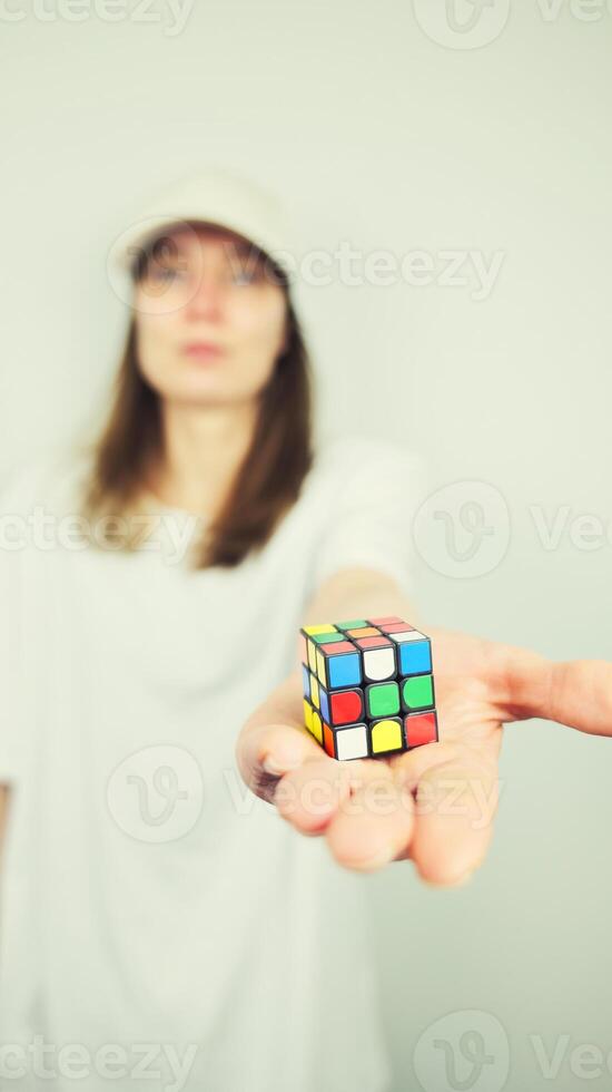 Portrait of beautiful Caucasian young female model holding Rubik's cube isolated on white background, copy space area photo