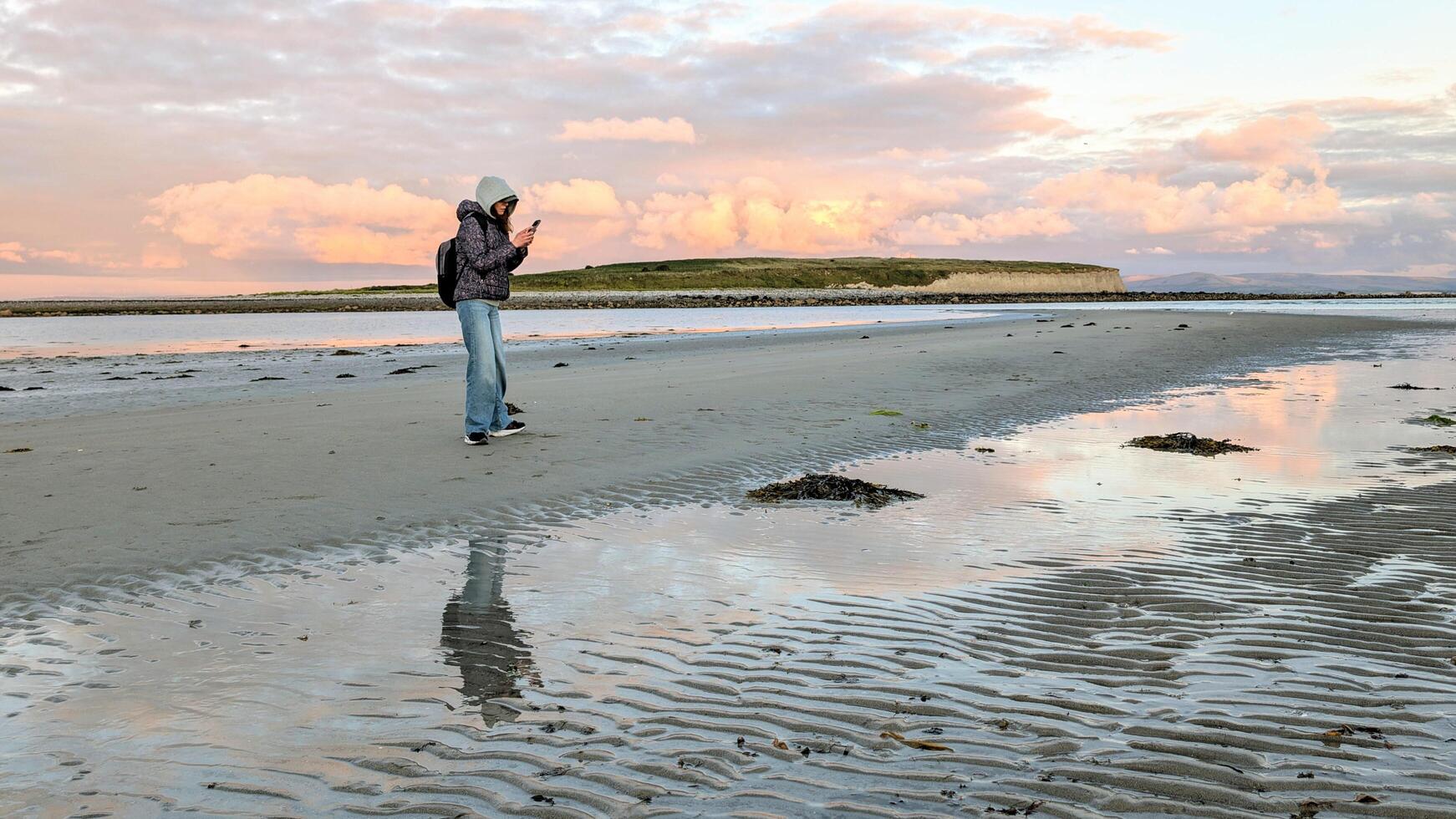 woman hiker backpacker enjoying coastal sunset scenery at sandy Silverstrand beach, Galway, Ireland, adventure and lifestyle concept, people in nature background photo