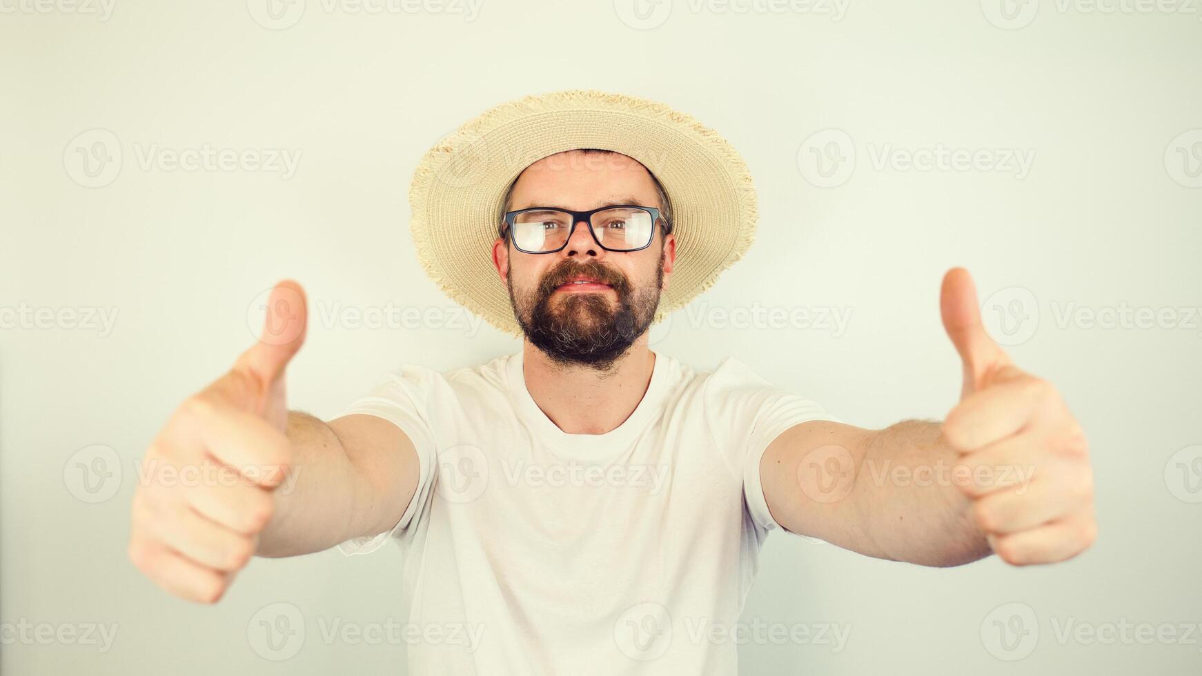 portrait of handsome bearded man with straw hat and glasses smiling, thumbs up gesture, wearing white shirt , isolated on white background photo